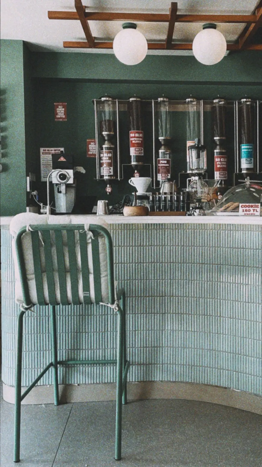 The counter at the café, green tiles and the coffee machine ready for the morning