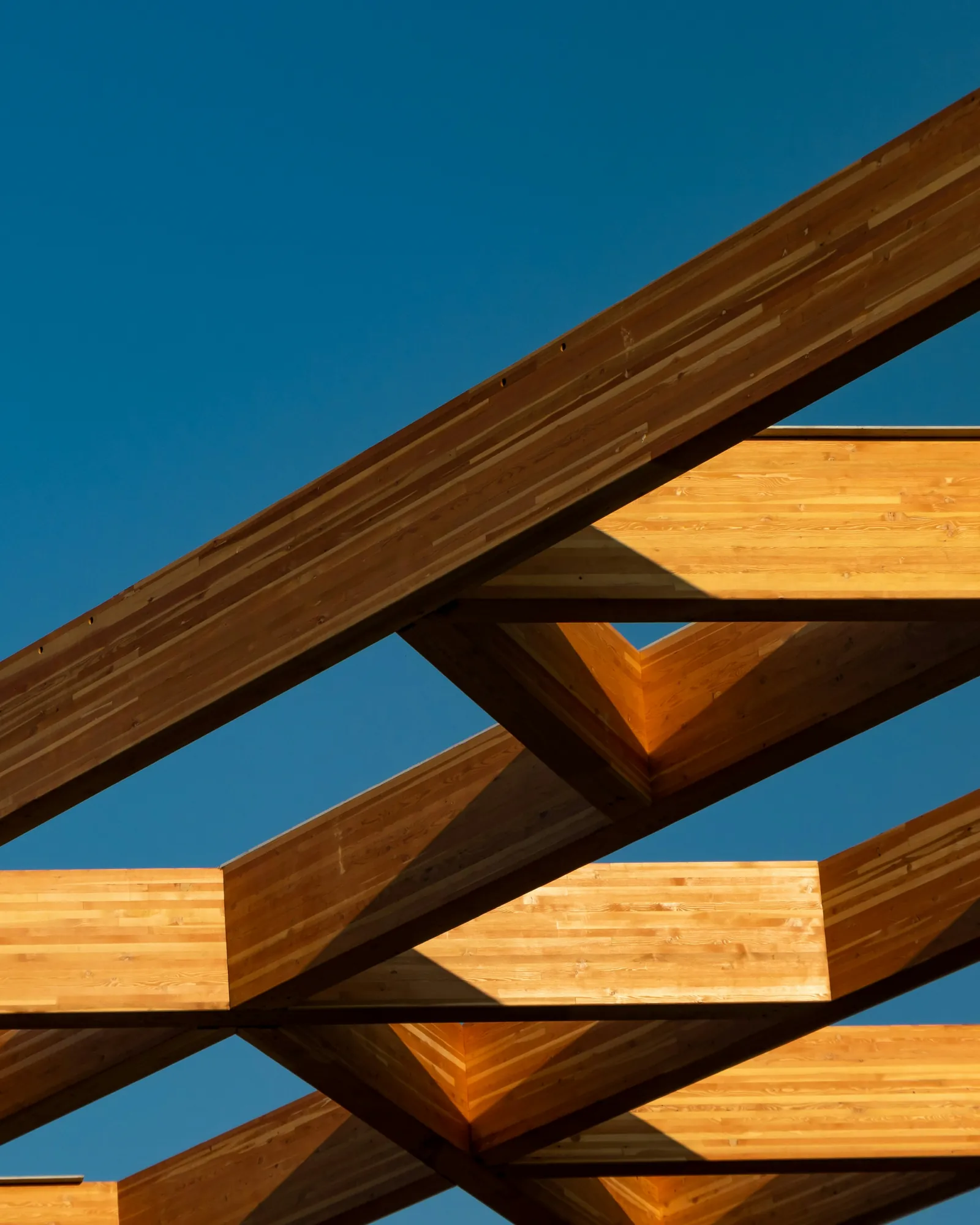 Timber beams crossing against a blue sky