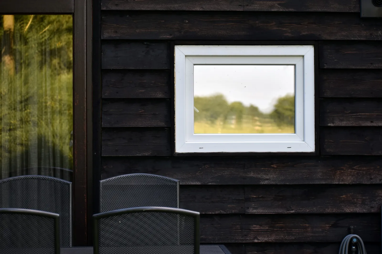 A square window set into black timber cladding