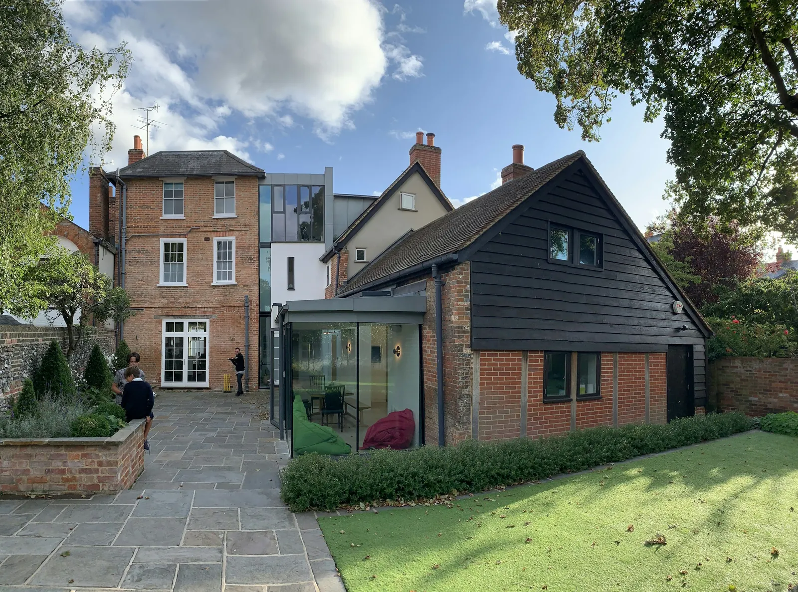 The back of a brick house with a glazed link and a black timber extension