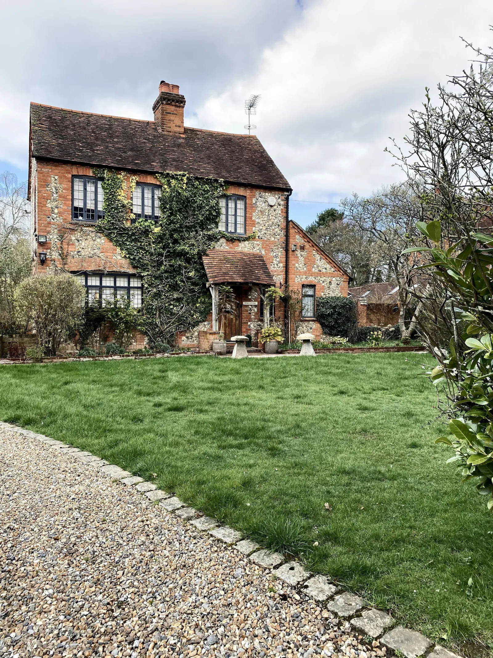 A brick and flint cottage in a garden