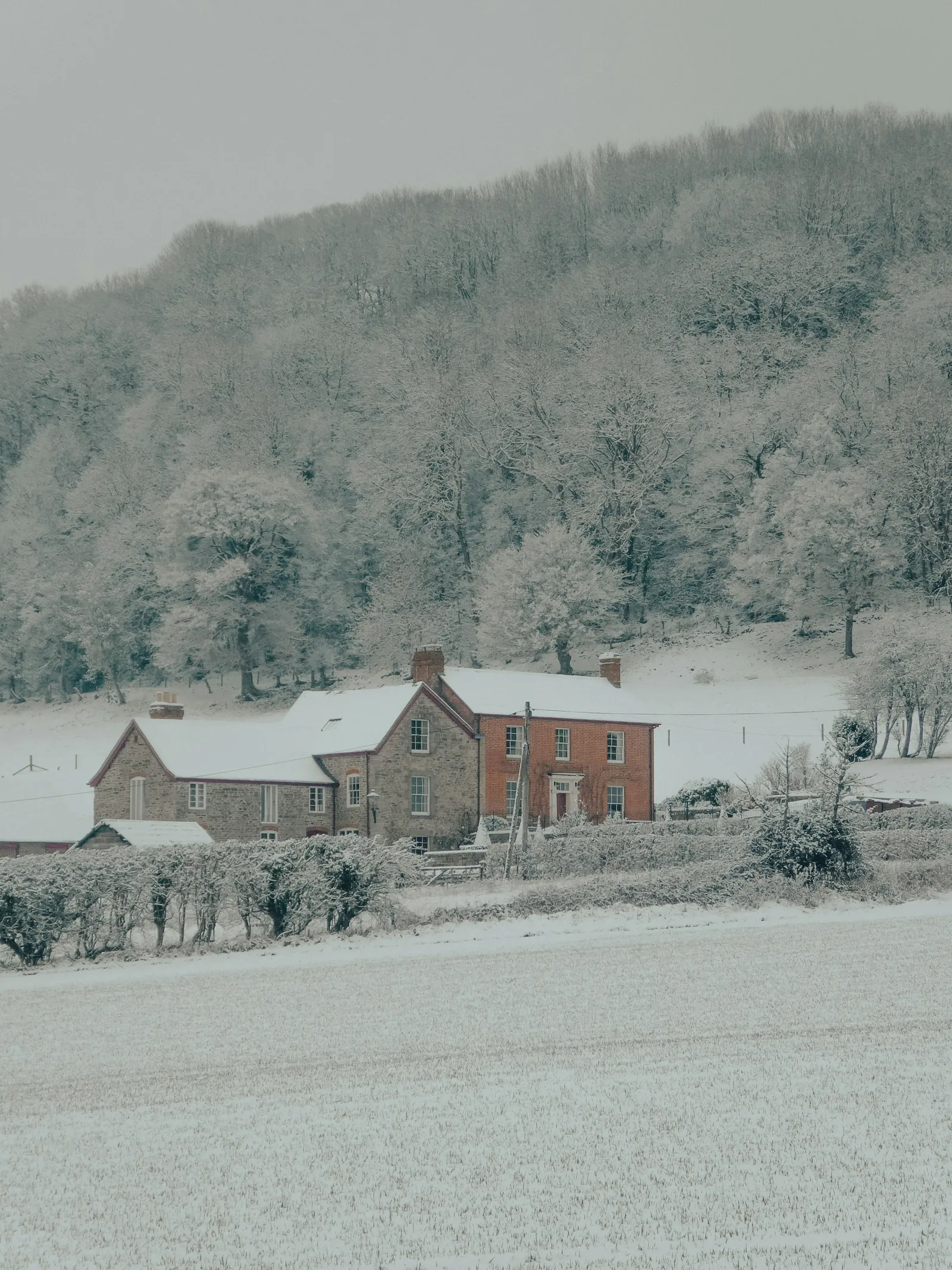 A brick farmhouse in a frosted valley under snow