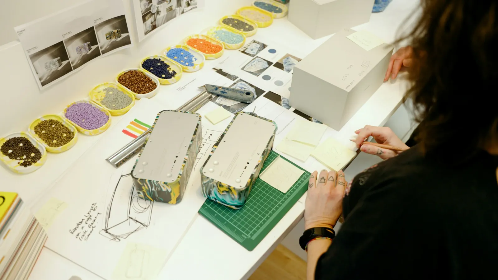 Hands assembling a white card model on a cutting mat