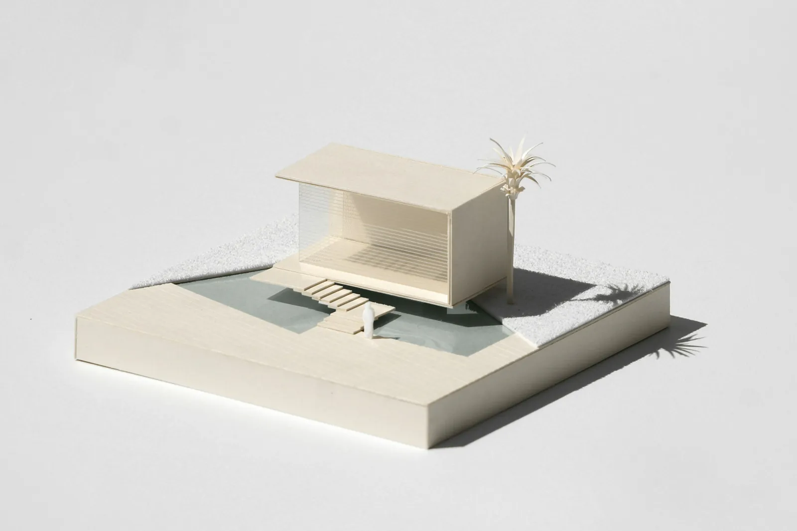 A white card model of a small house on a grey base