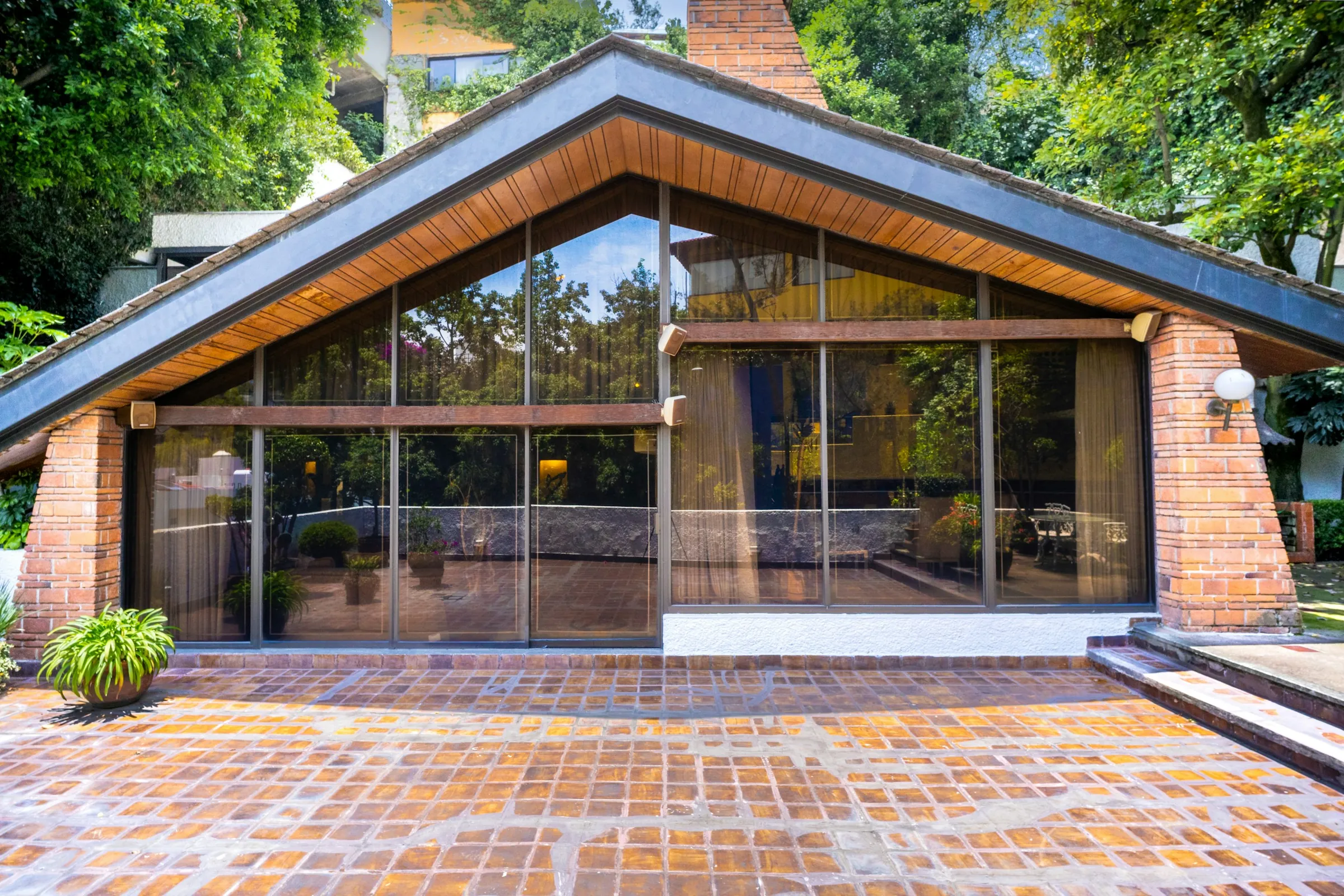 The Orchard Room: a glazed gable under a deep timber-lined roof, opening onto a brick terrace