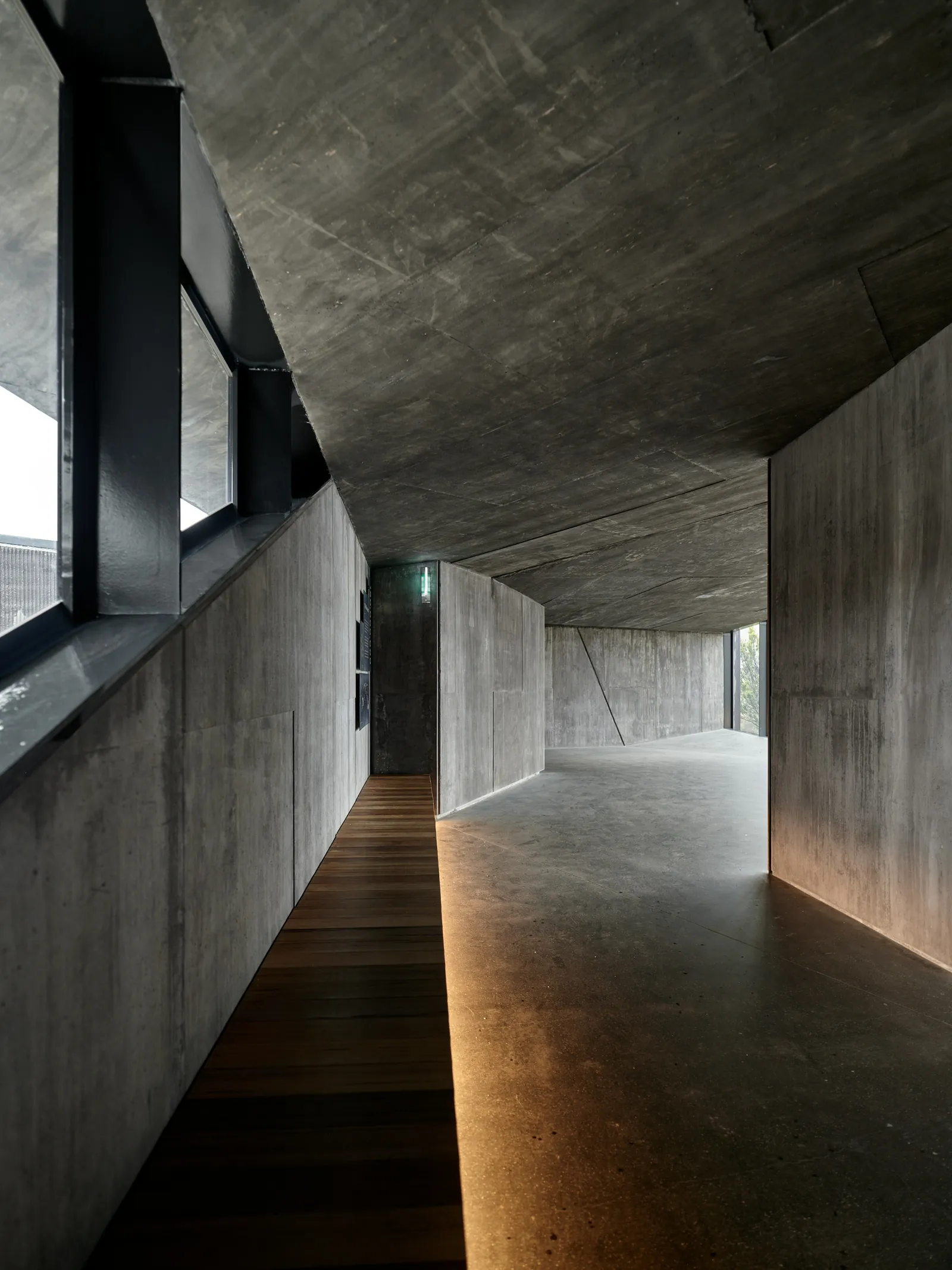 A narrow timber-floored walkway between concrete walls