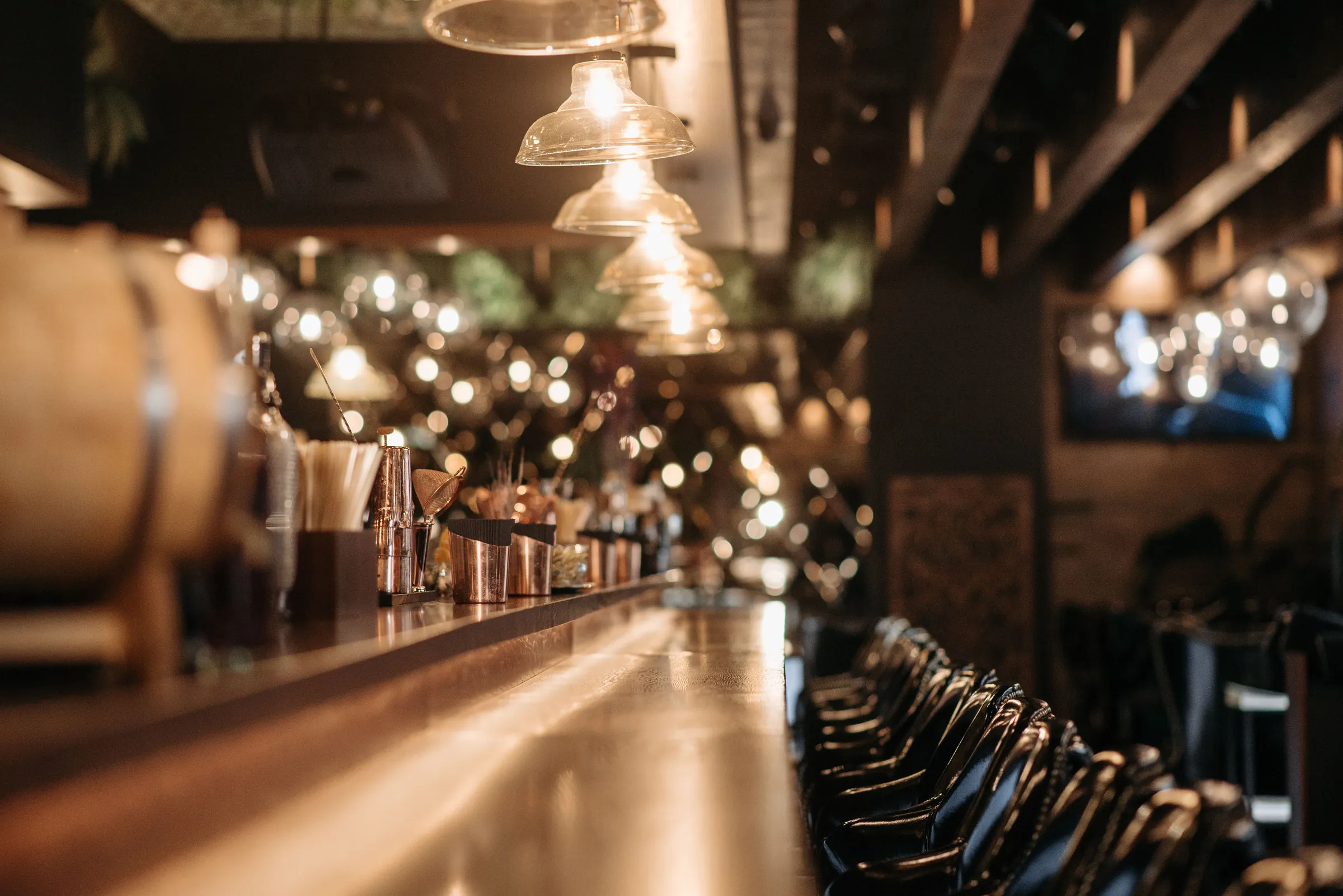 The long bar at night, copper and glass under low lights