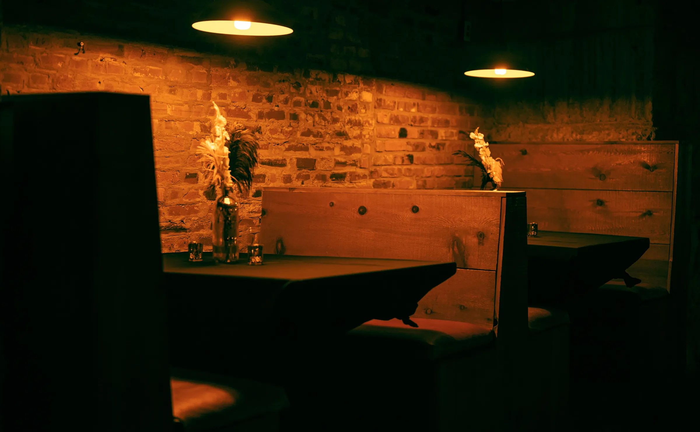 A candlelit wooden booth against a brick wall in a quiet corner