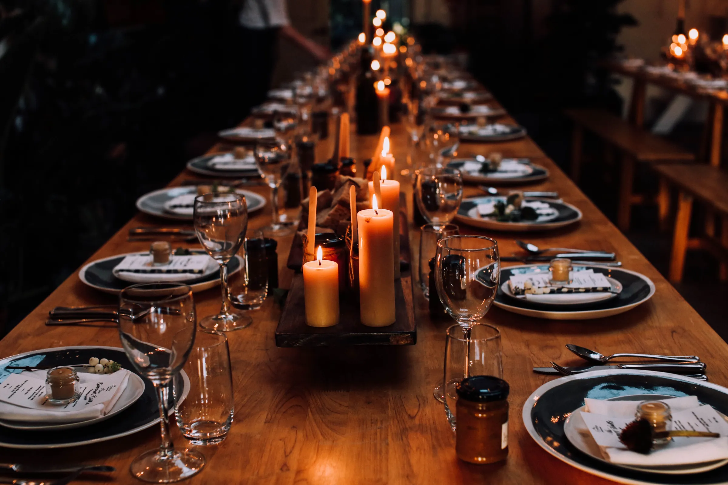 A long wooden table laid for a feast with lit candles down the middle