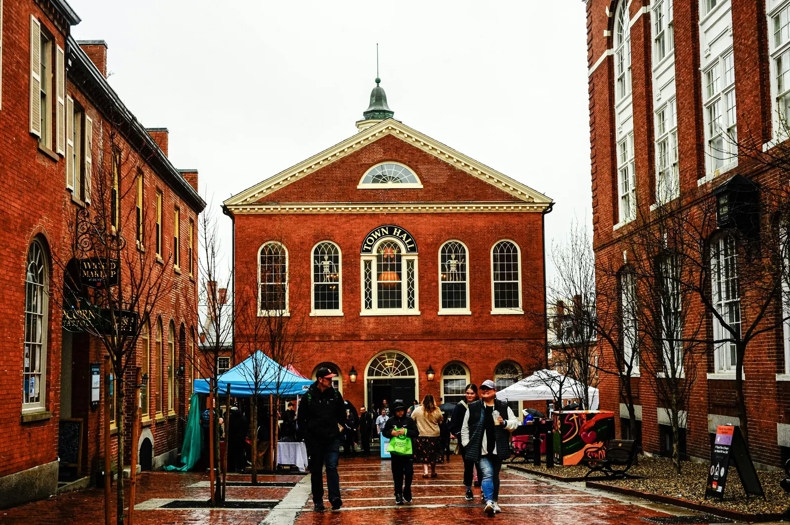 Market stalls outside a red-brick town hall on a wet morning