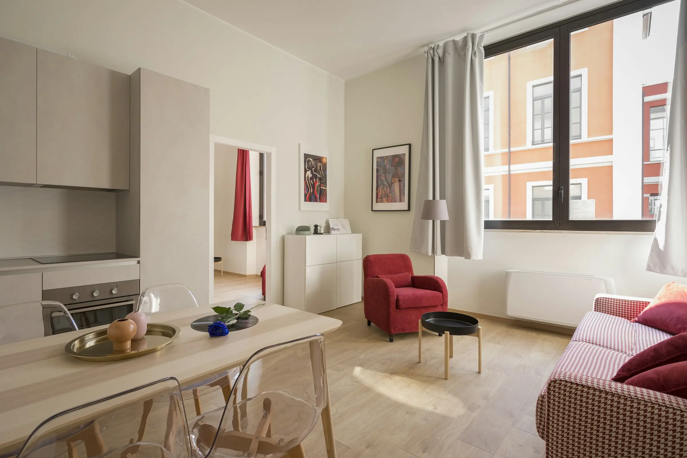 A tidy one-bedroom flat with a sofa, plants and tall windows