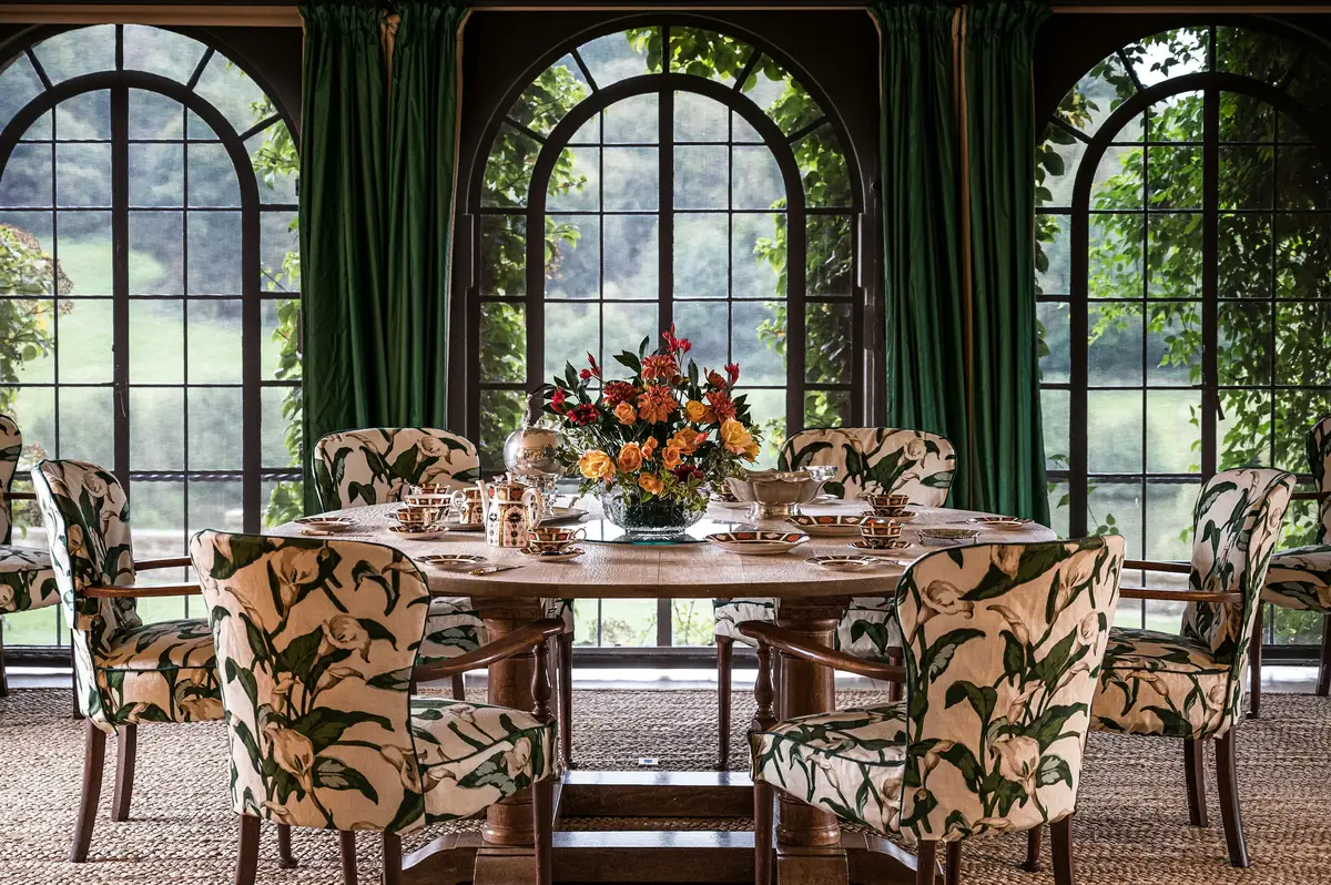 A dining room with arched windows and a long table, photographed for a listing