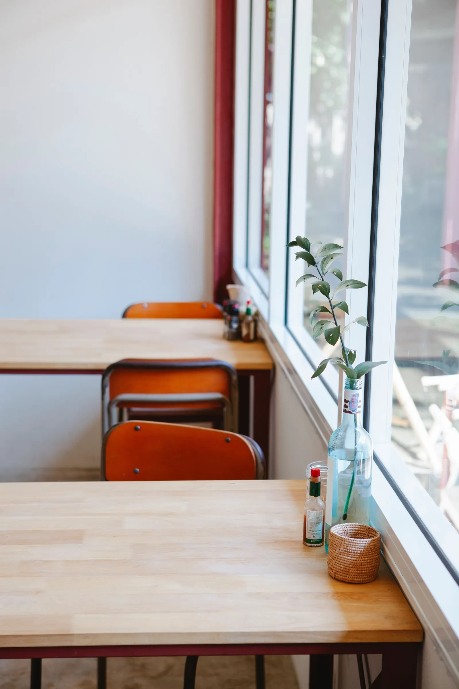 A quiet café in the morning, wooden tables and chairs by a tall window
