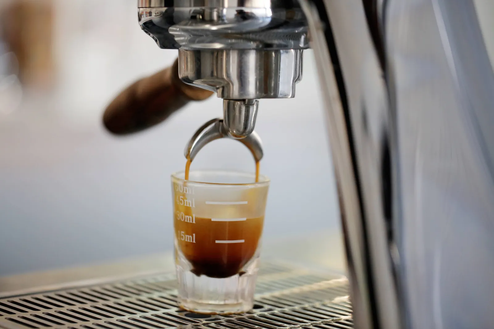 Espresso running into a measured shot glass under a machine group head