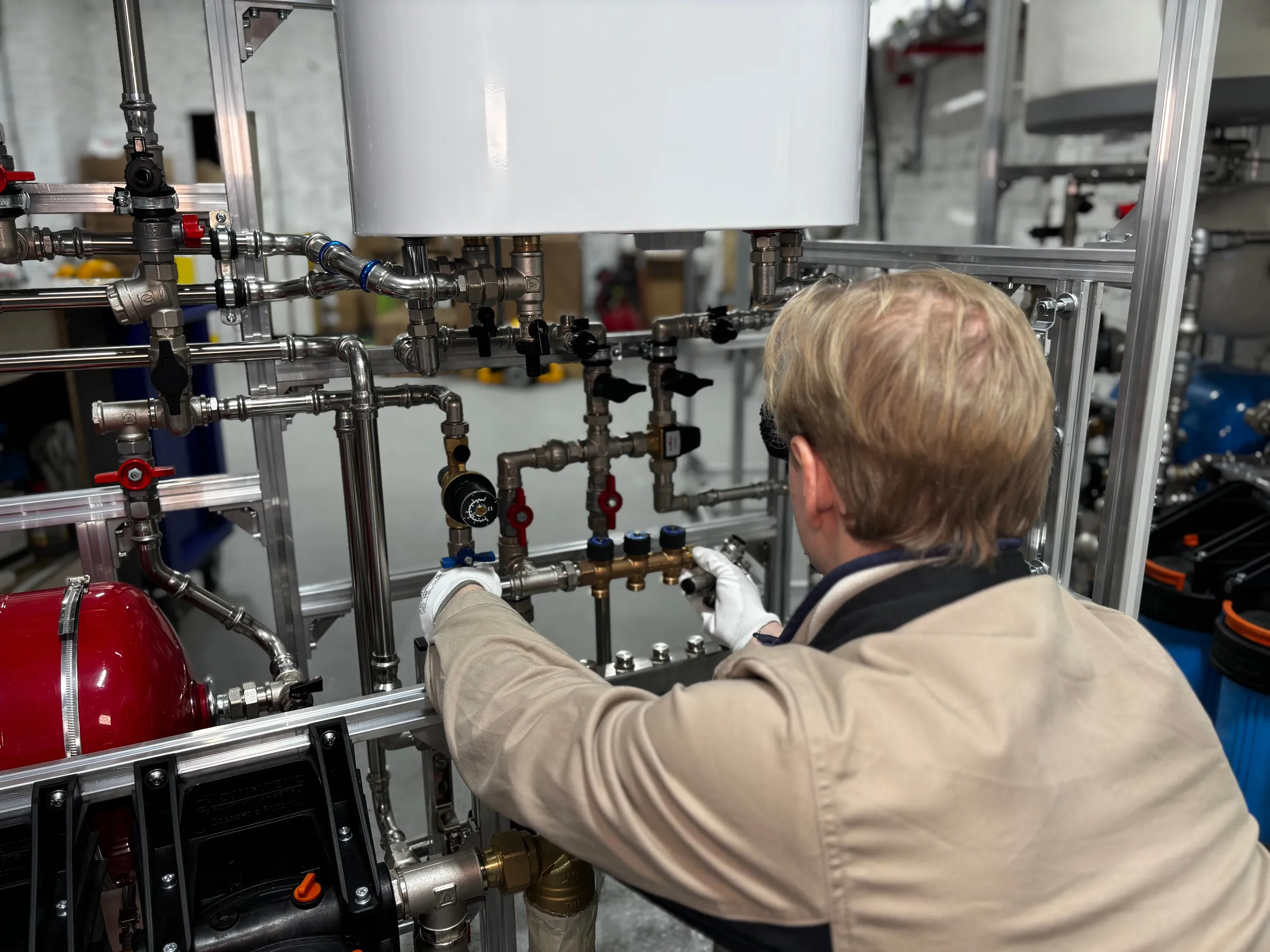 An engineer connecting pipework to a heating manifold with pressure gauges