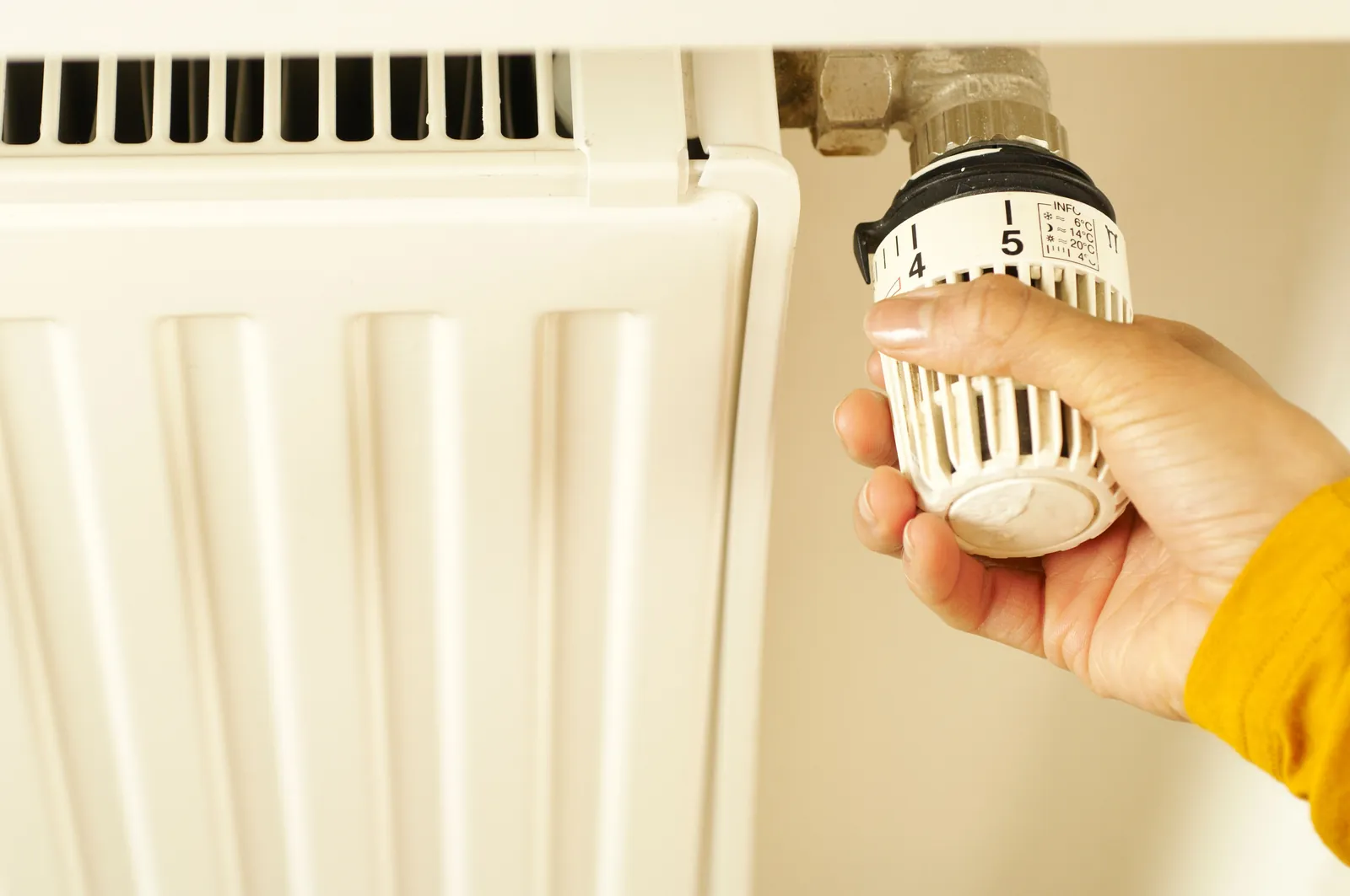 A hand turning a thermostatic radiator valve