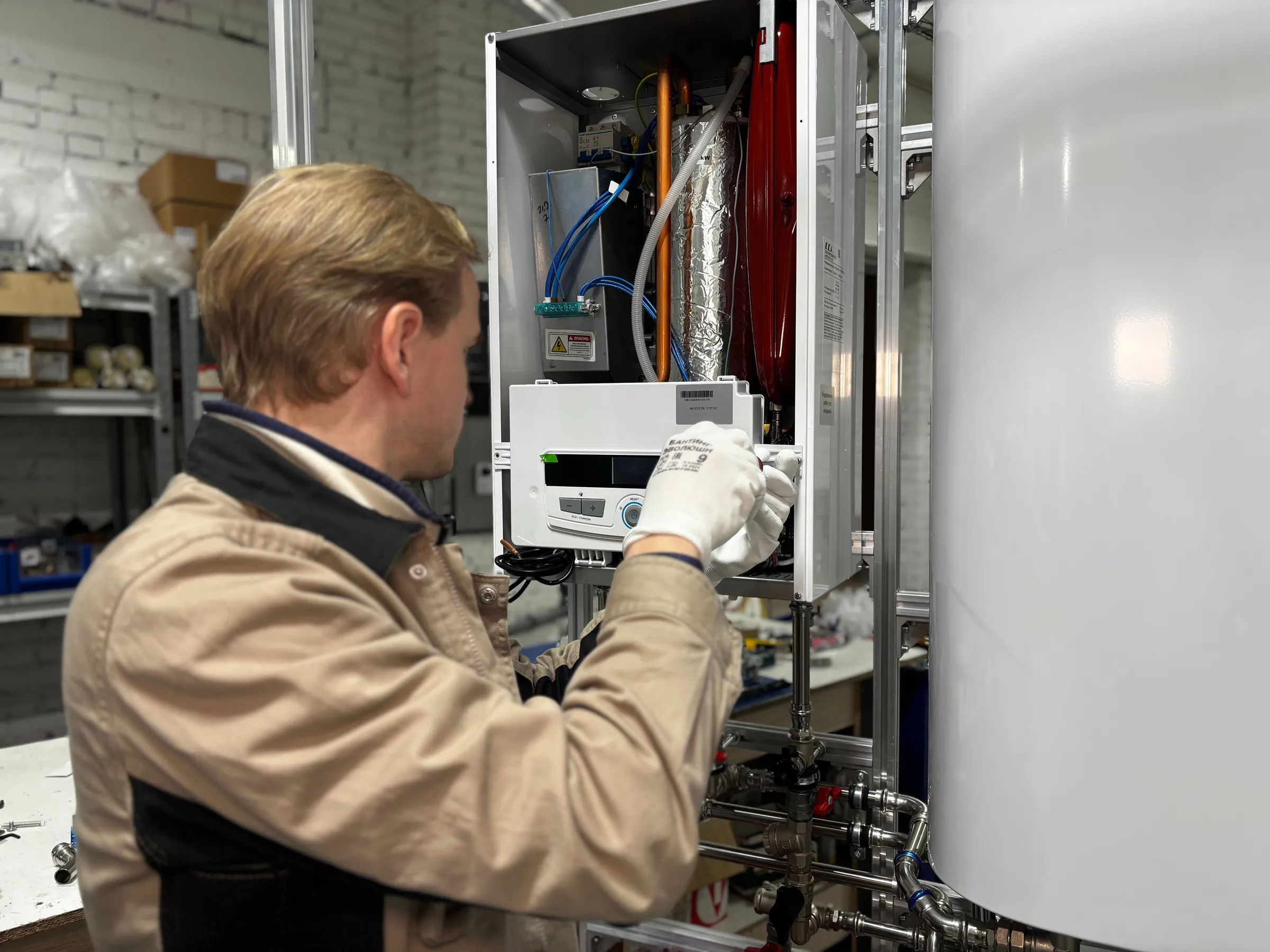 An engineer working inside an open wall-mounted boiler with the casing removed