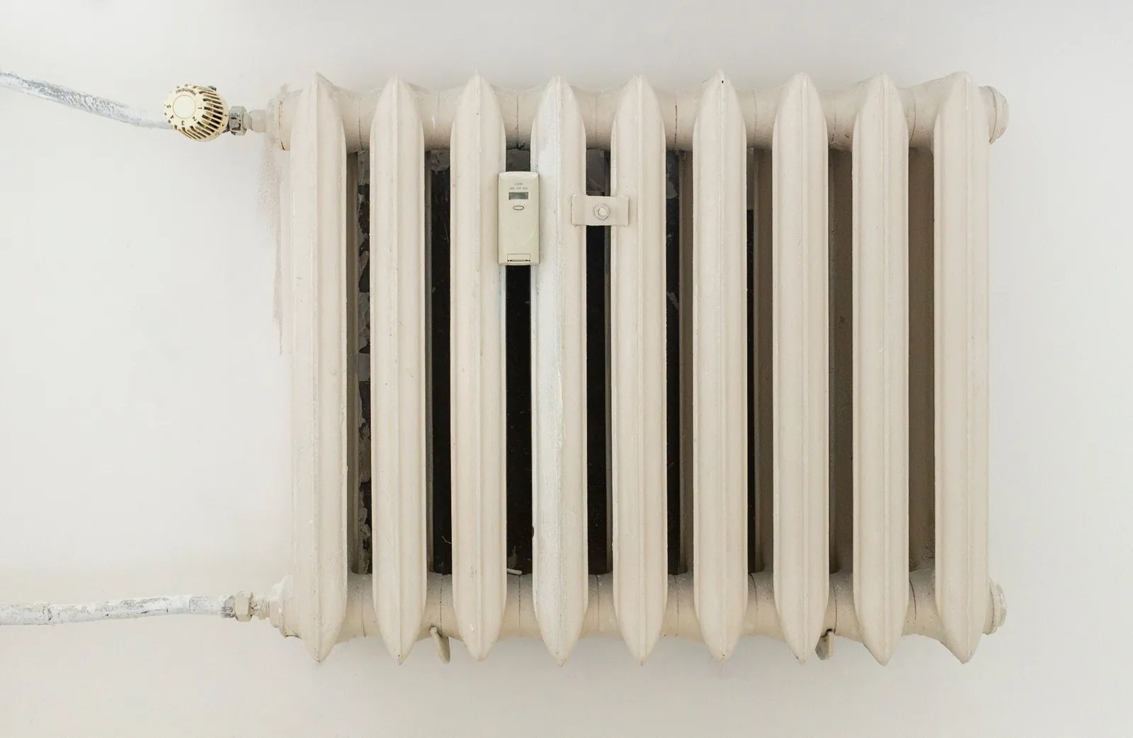 A white cast iron column radiator against a pale wall
