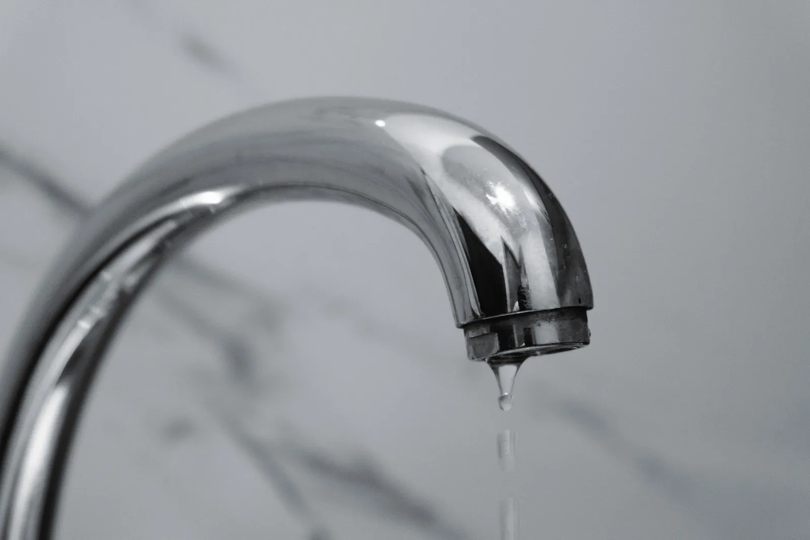 A chrome tap with a single drip hanging from the spout