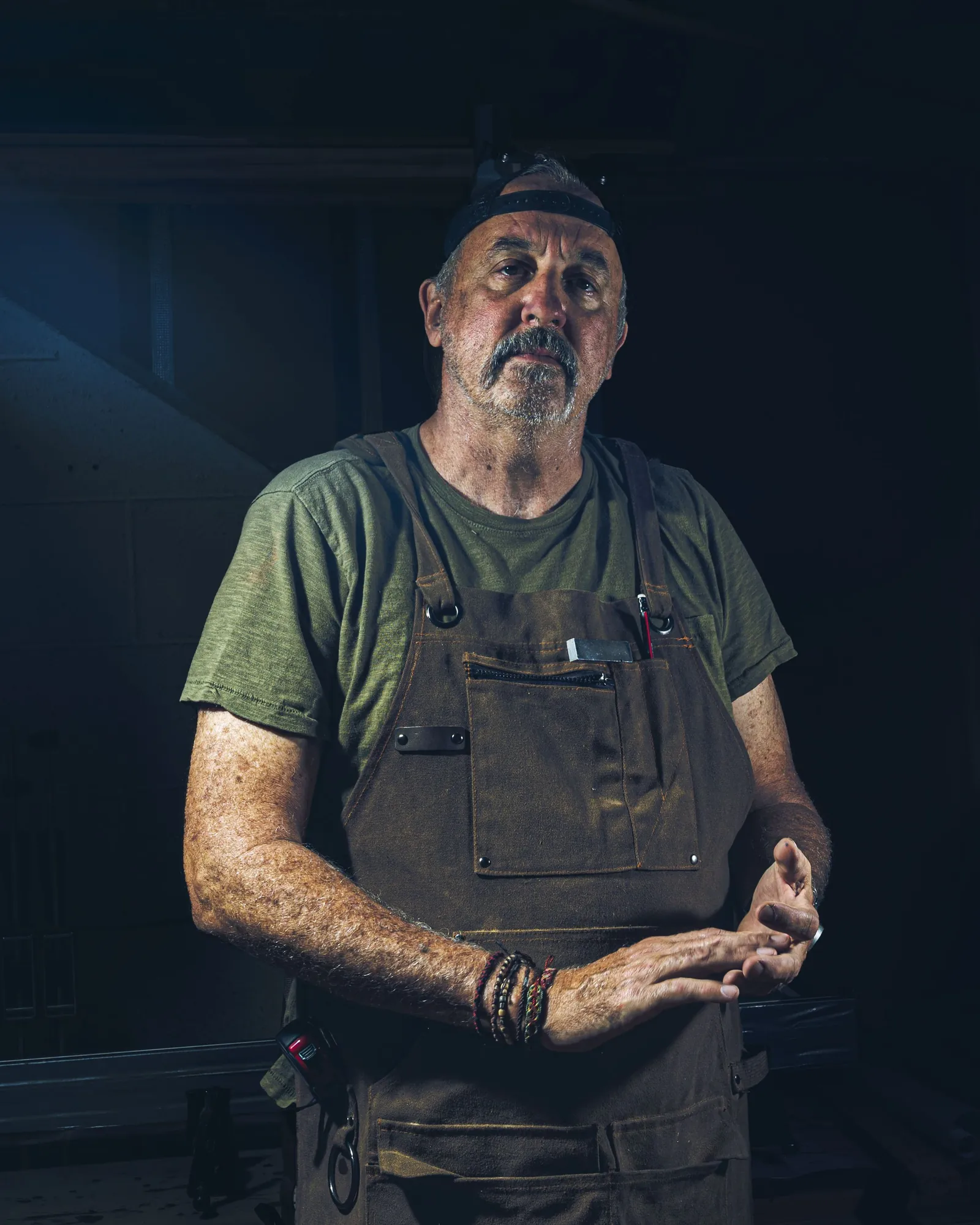 Dan, an older engineer in a leather work apron, photographed in the yard