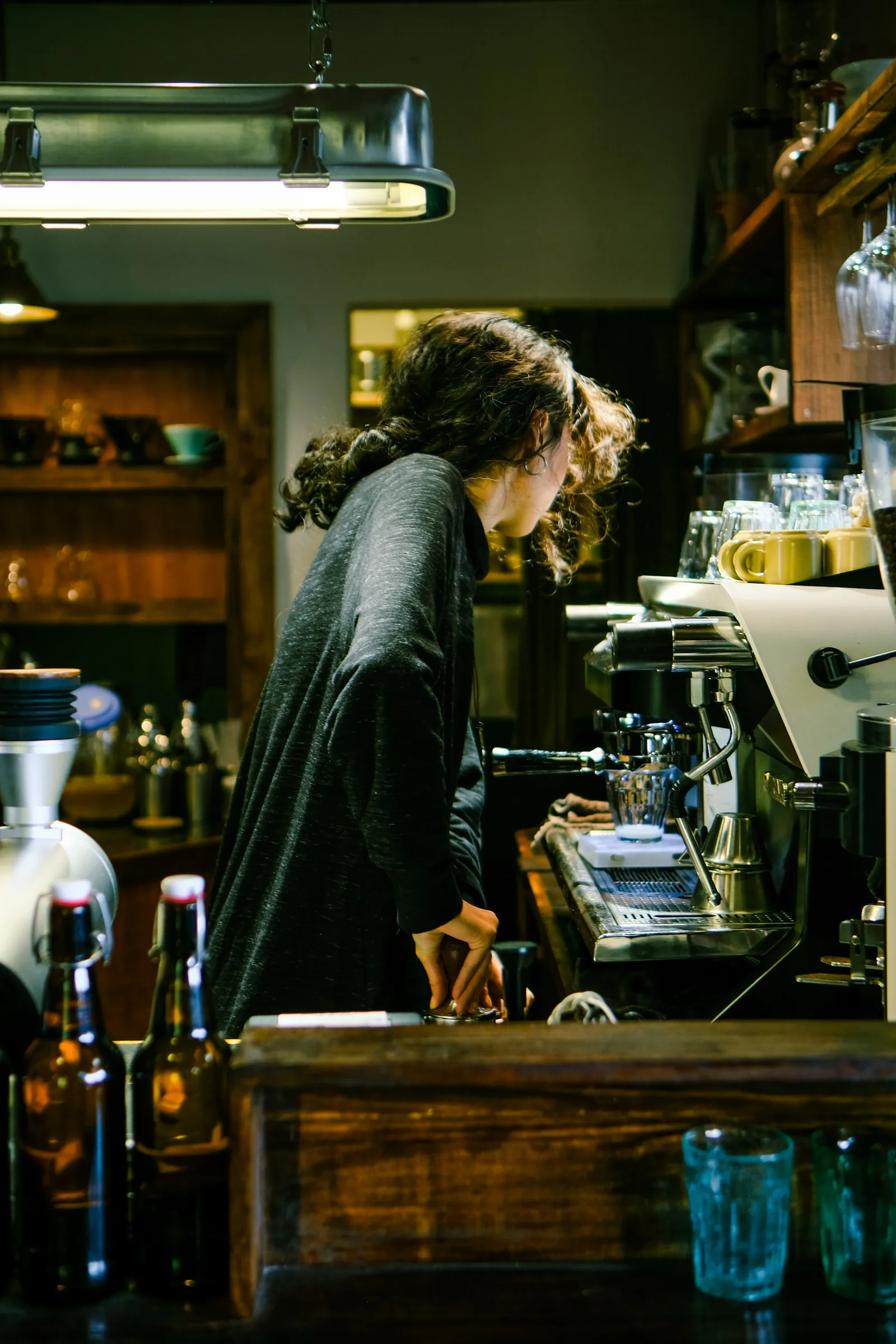 A barista tamping coffee behind the counter of a small café