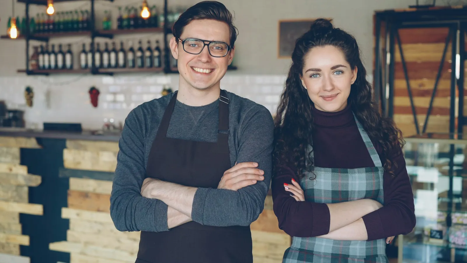 Two café owners in aprons standing behind their counter