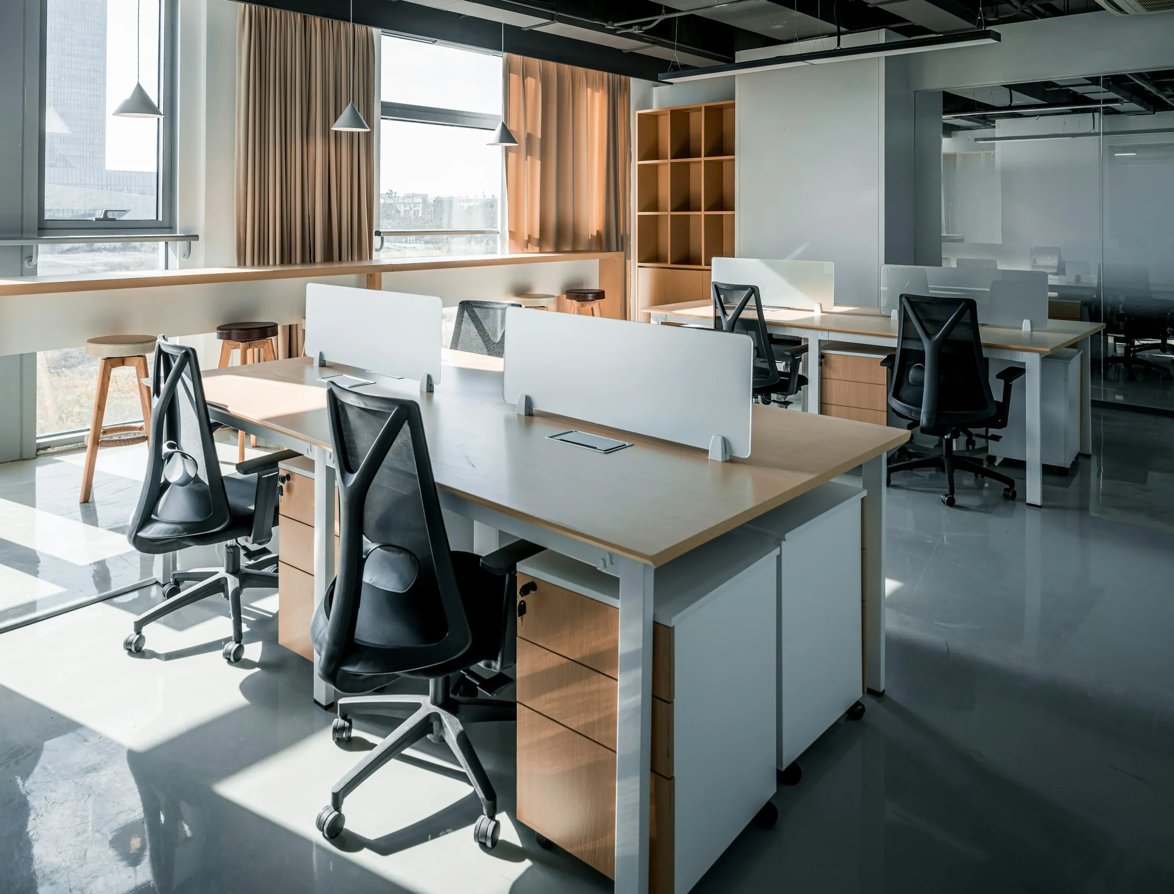 Desks with monitors in a sunlit office with wooden floors