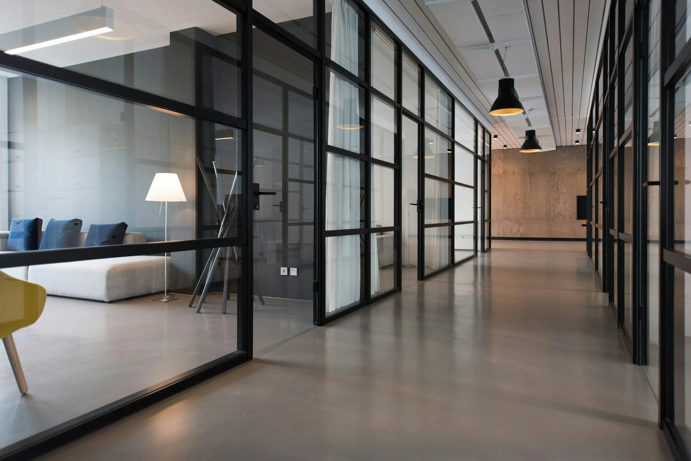 A glass-walled corridor between offices, flooded with daylight