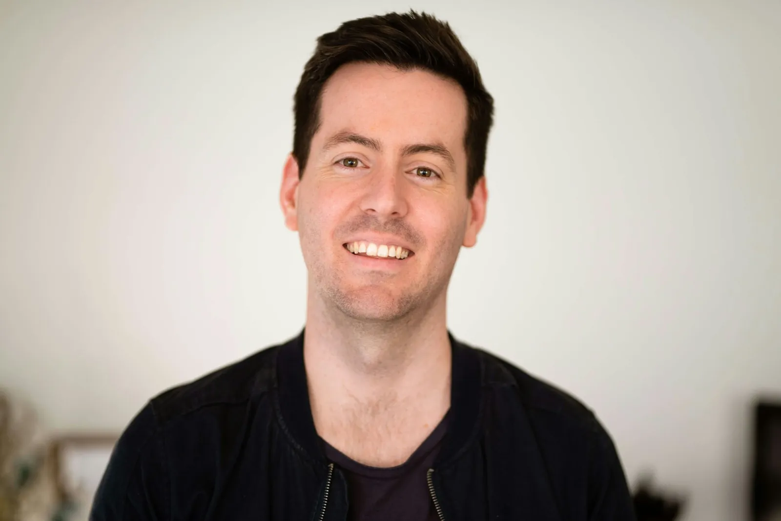 Sam Whitlock, smiling, photographed in a plain studio