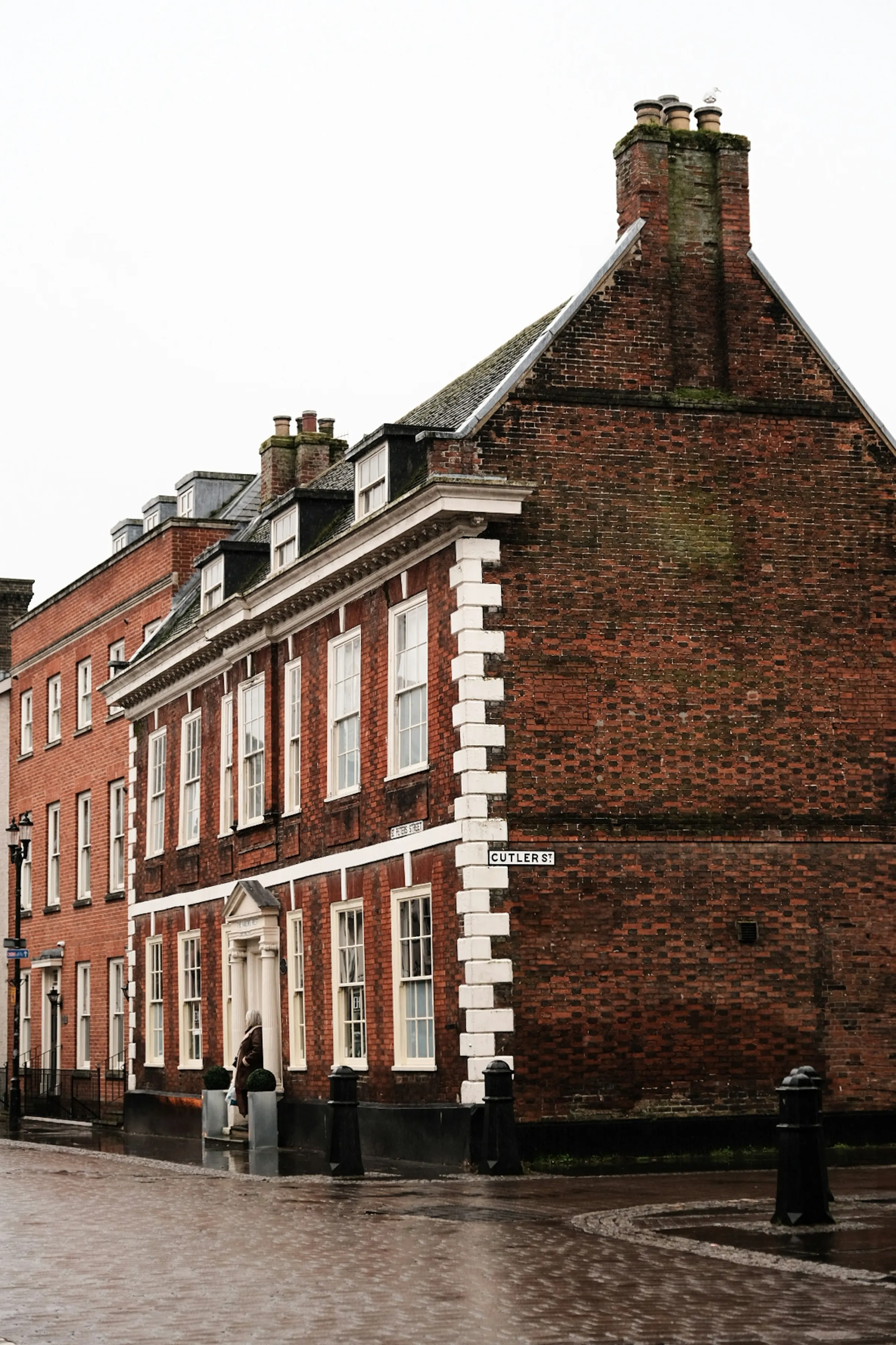 A red-brick Georgian corner building on a wet market-town street