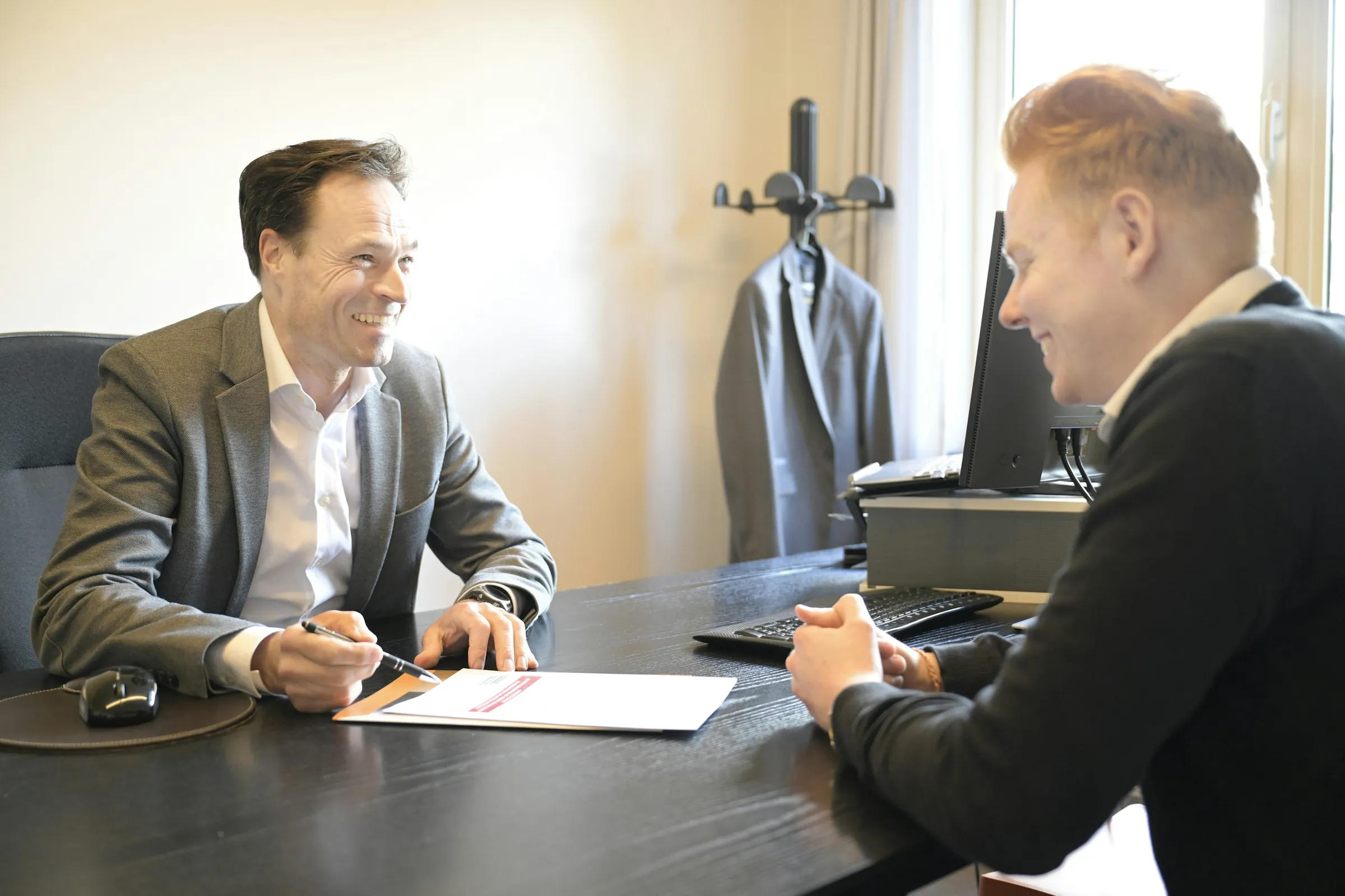 Two directors going through documents together at a desk by the window
