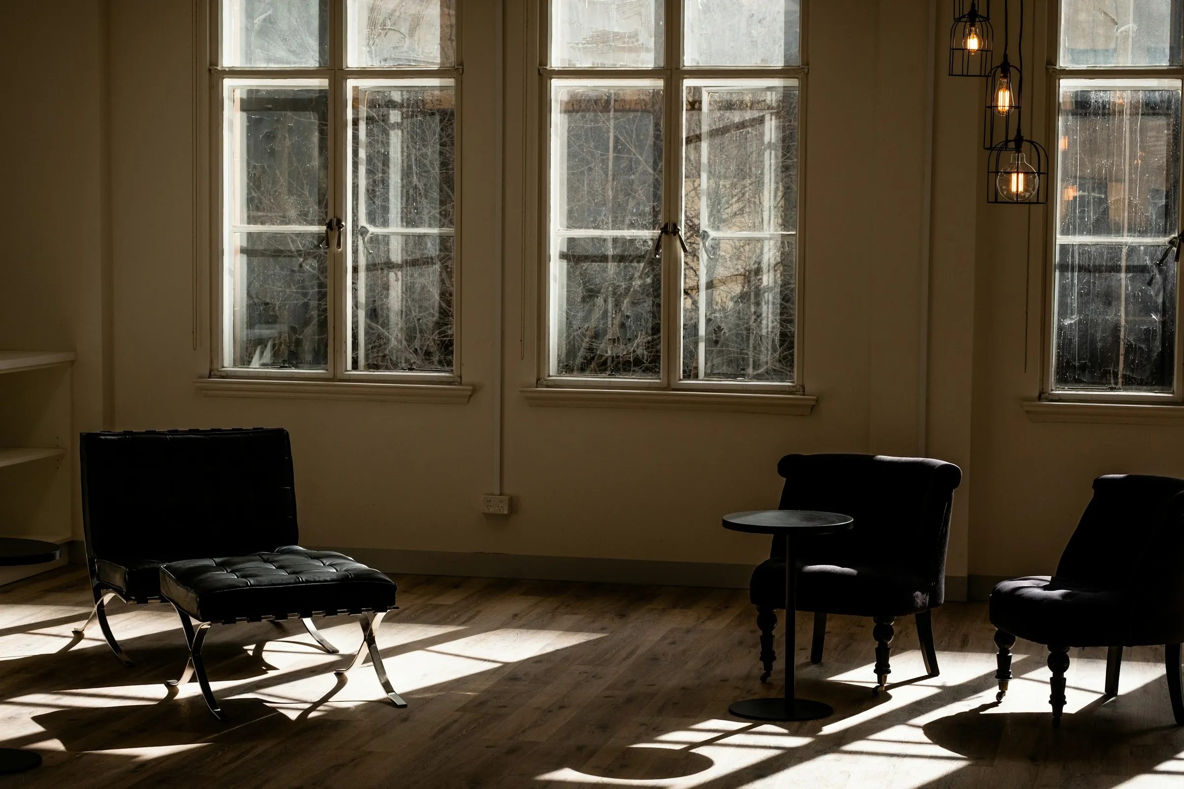 A leather chair by a tall sash window in a brick-walled office