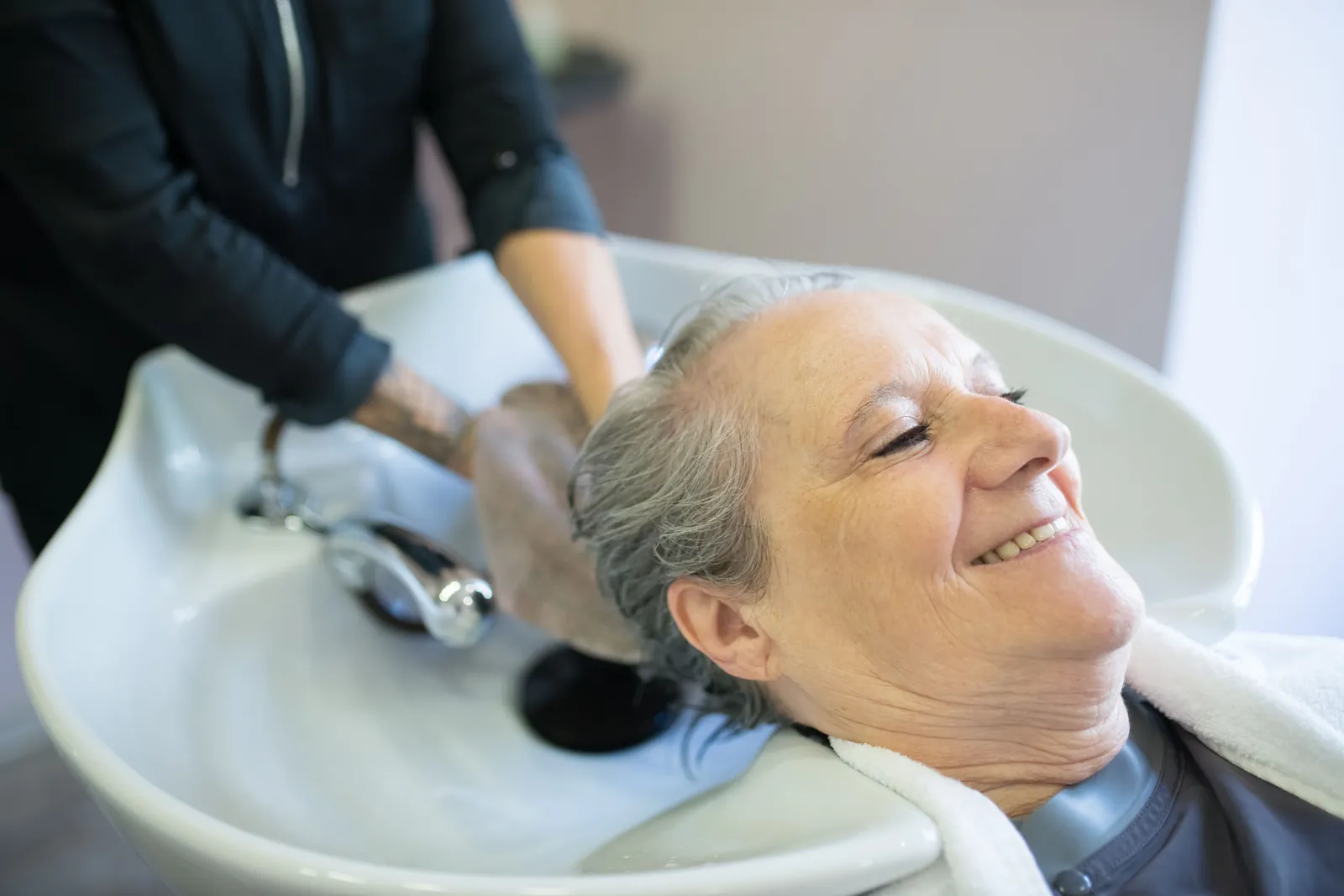 A client smiling at the basin while her hair is washed