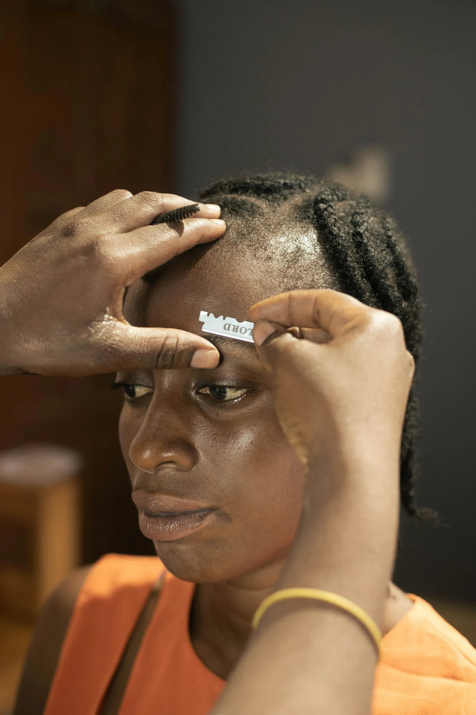Hands shaping an eyebrow with a small brush