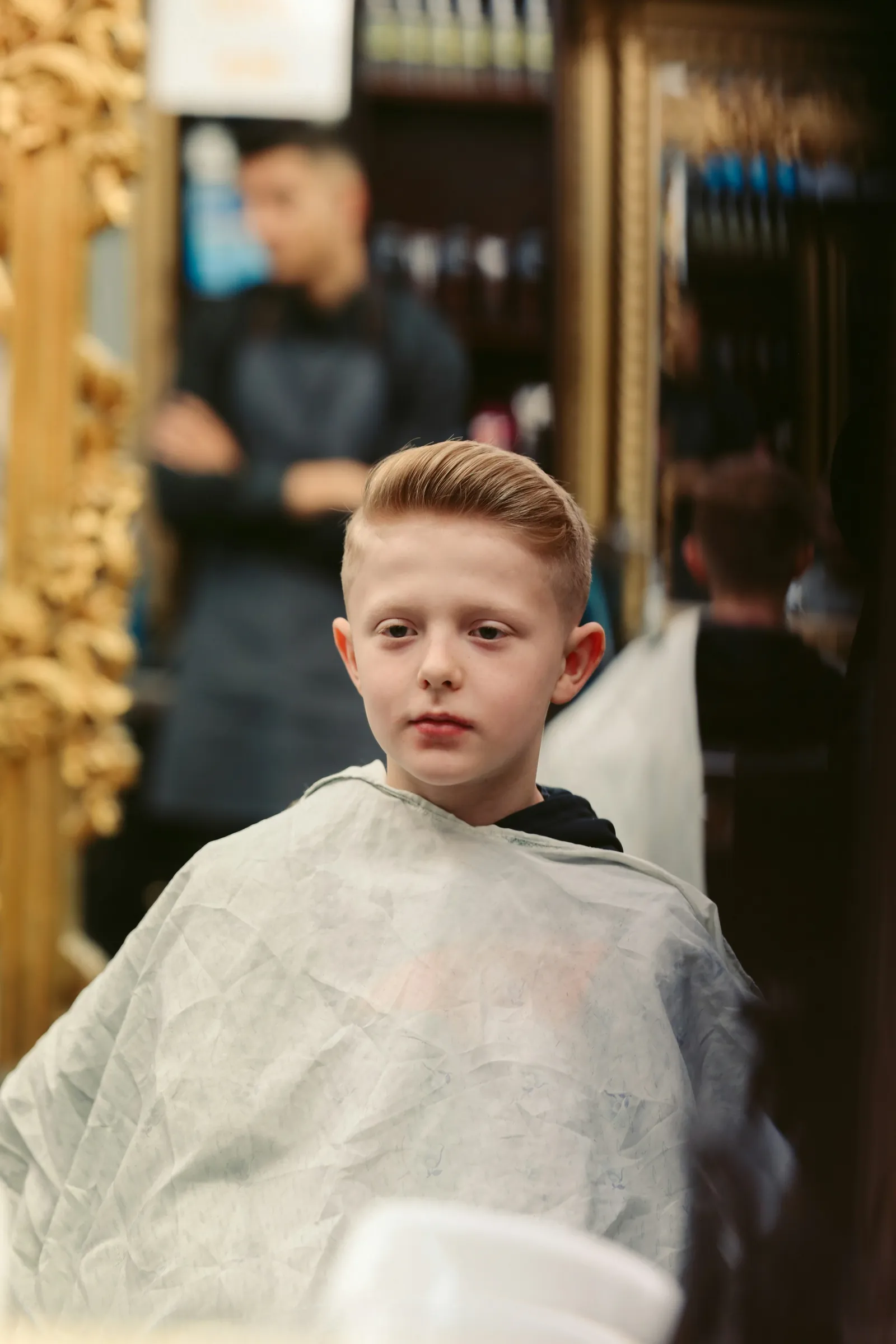 A boy in a cape waiting for his haircut