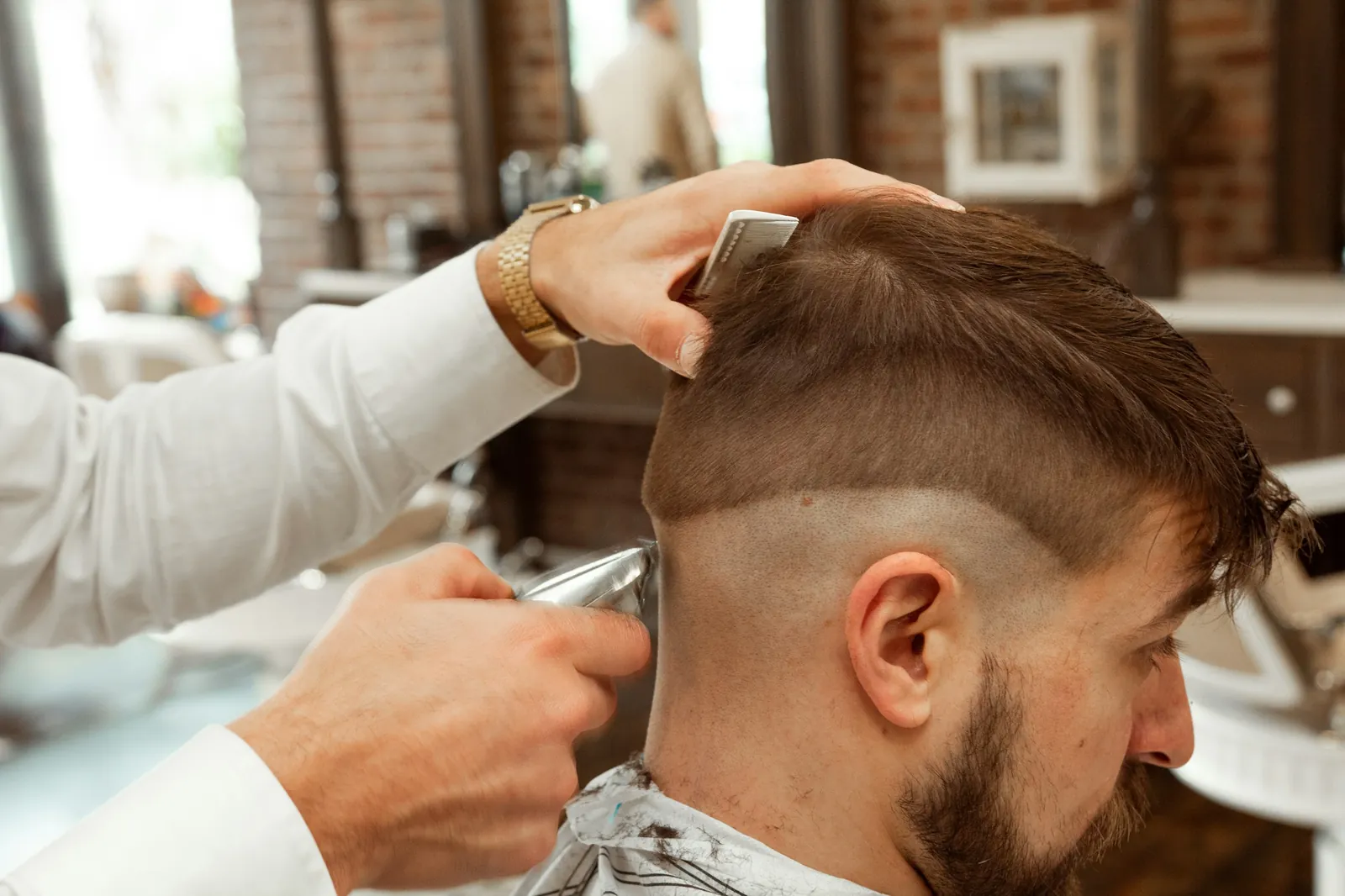 A man having his hair cut with scissors in a bright salon