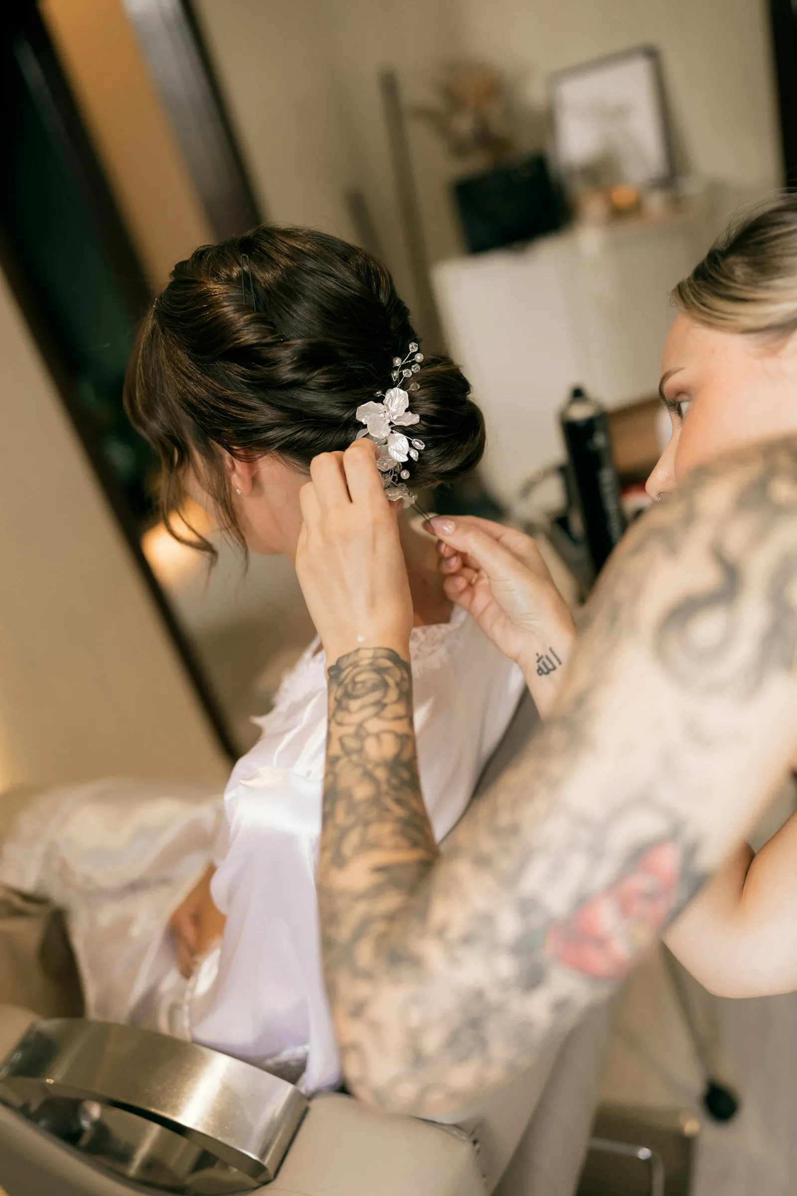 A bride having her hair pinned up with flowers