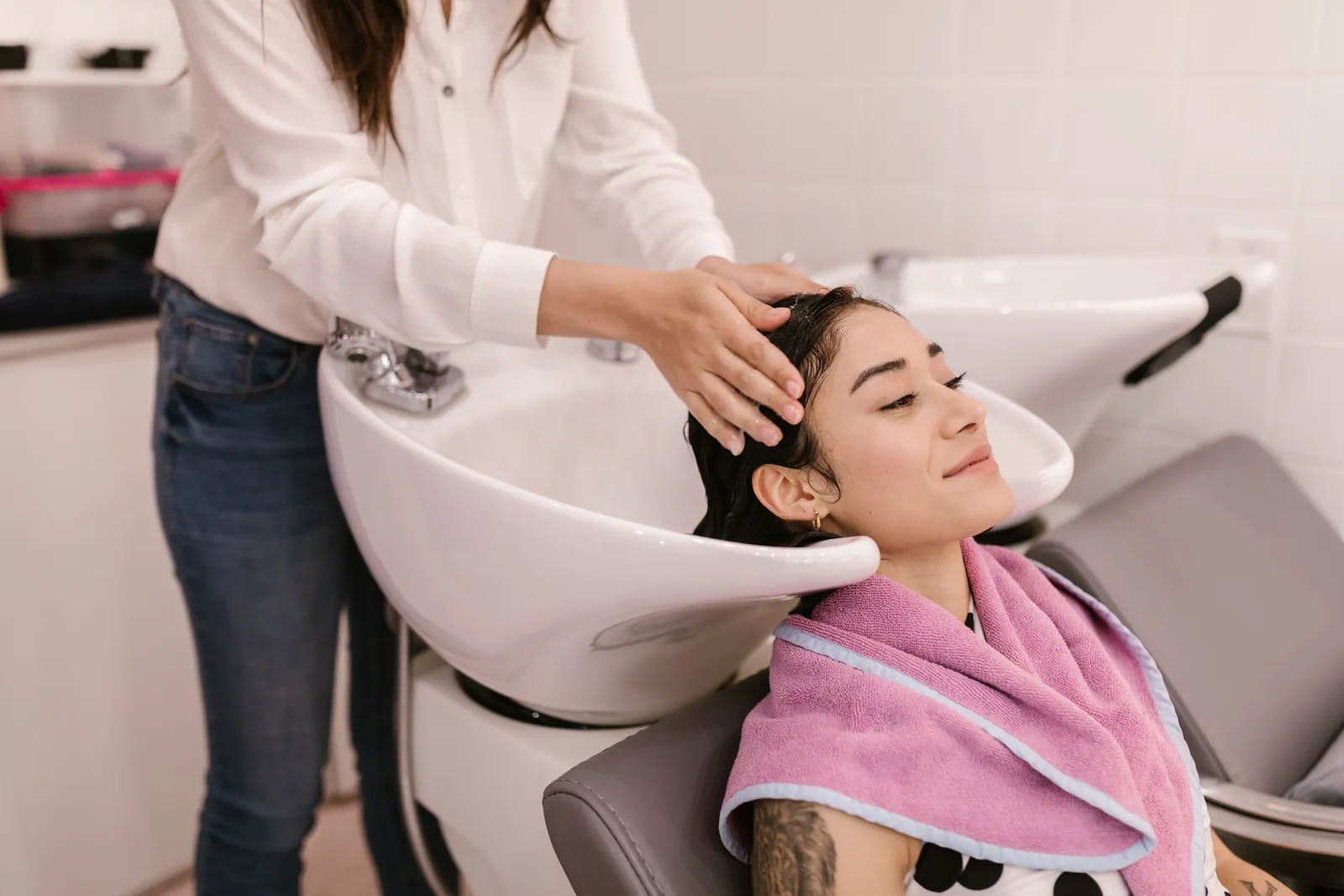 A client at the basin with a treatment being worked through her hair