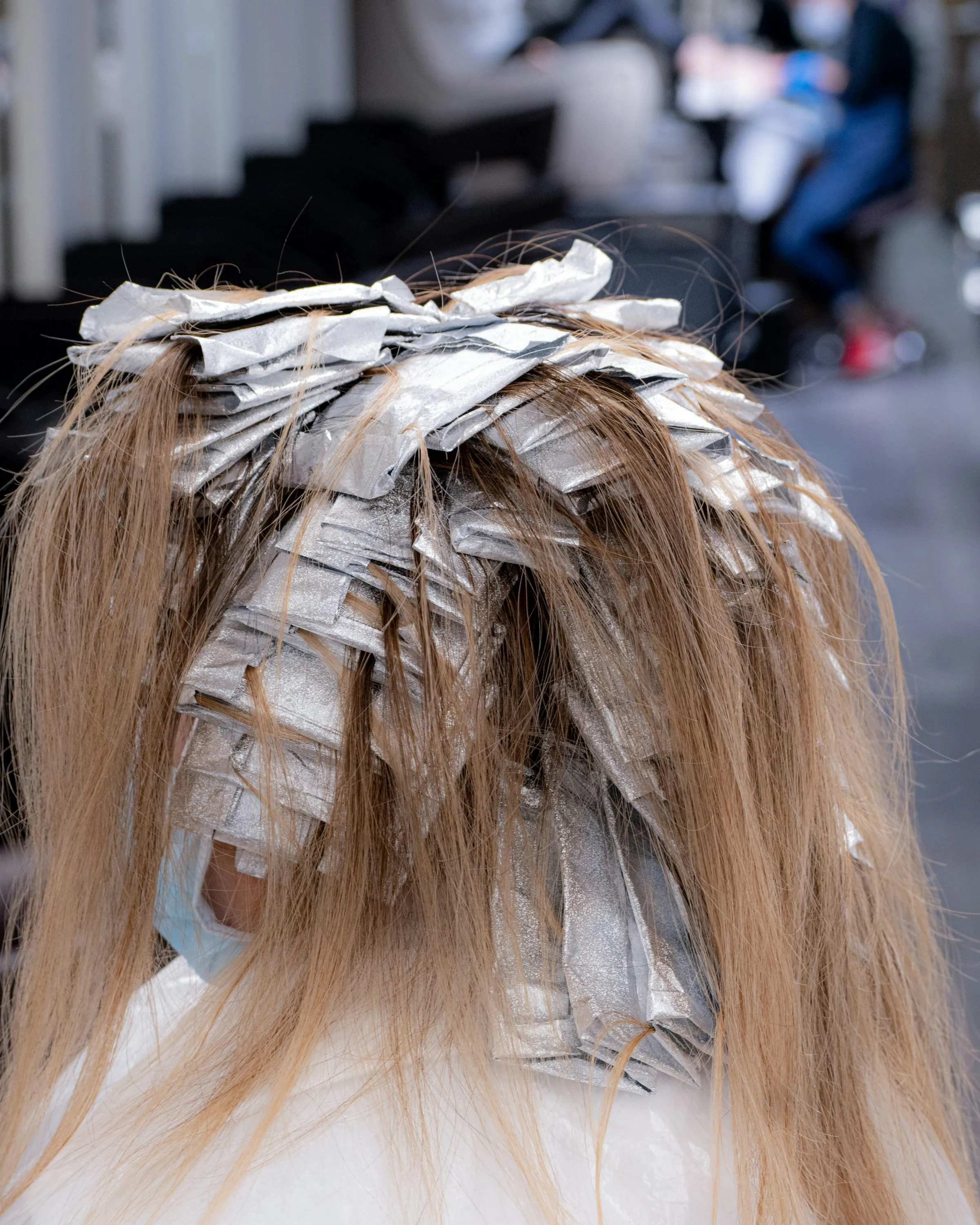 Foils packed through long dark-blonde hair in the chair