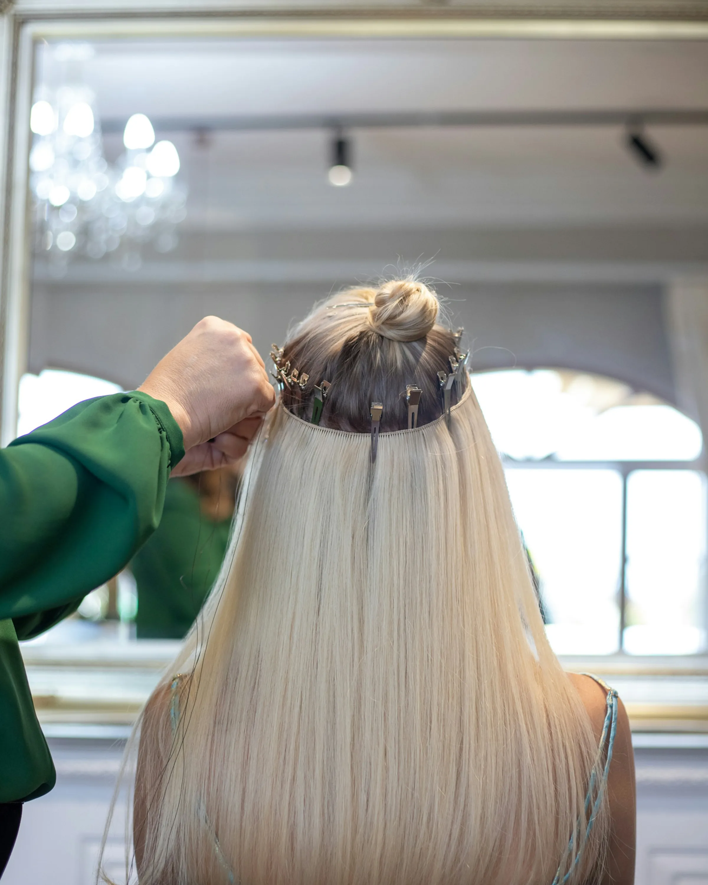Lengths being fitted at the back of blonde hair in the chair