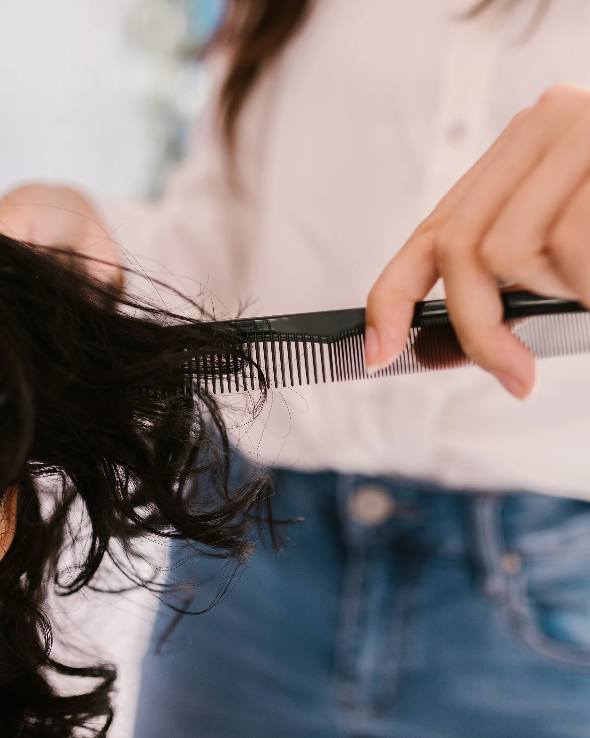 A comb and scissors working through dark curls