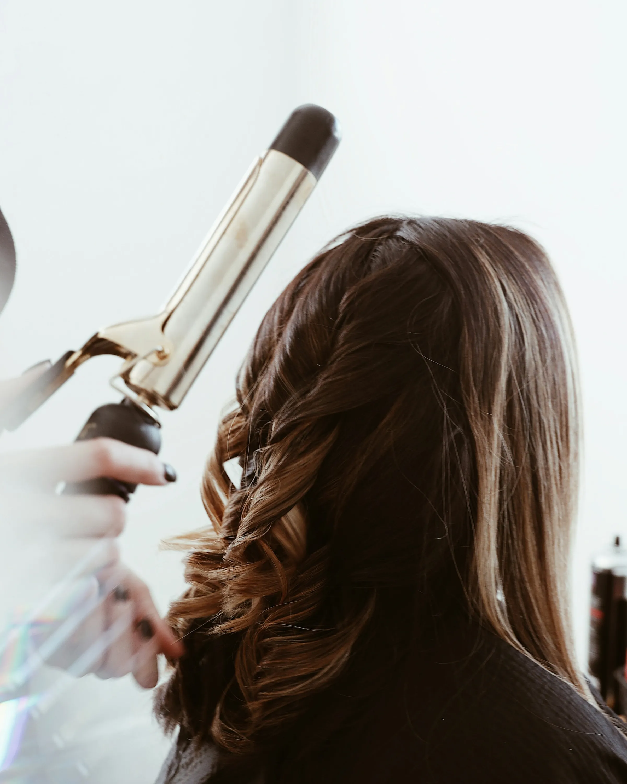 A curling wand working through dark-blonde balayage