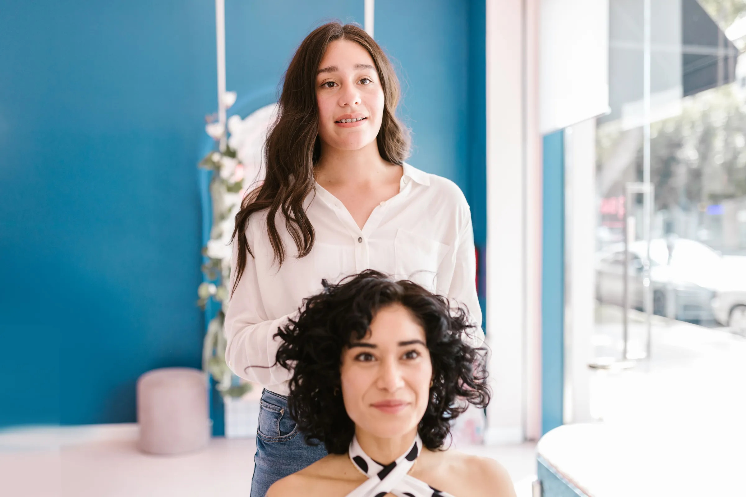 A stylist and client laughing together at the chair