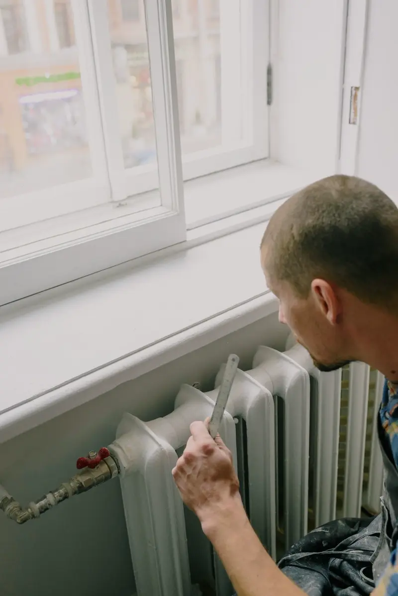 Checking a radiator under the window in a customer's home