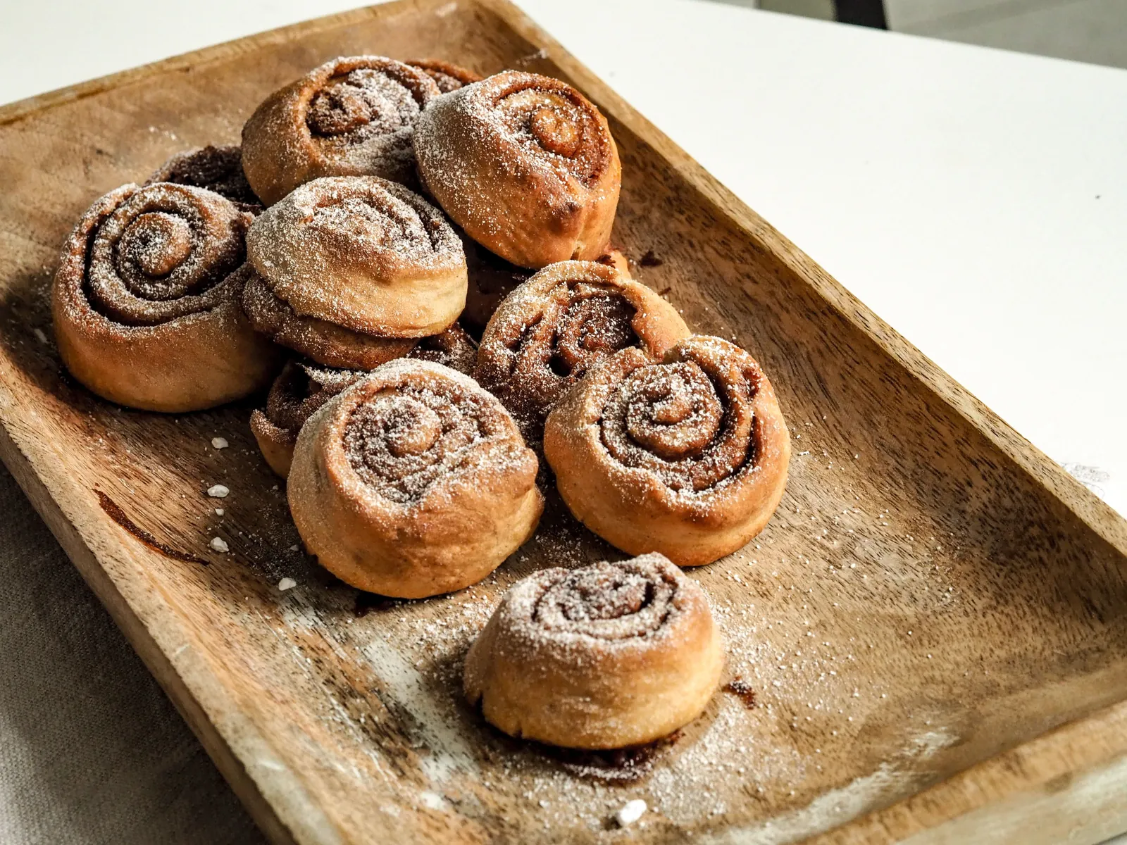 Cinnamon buns on a wooden tray, dusted with sugar, just out of the oven