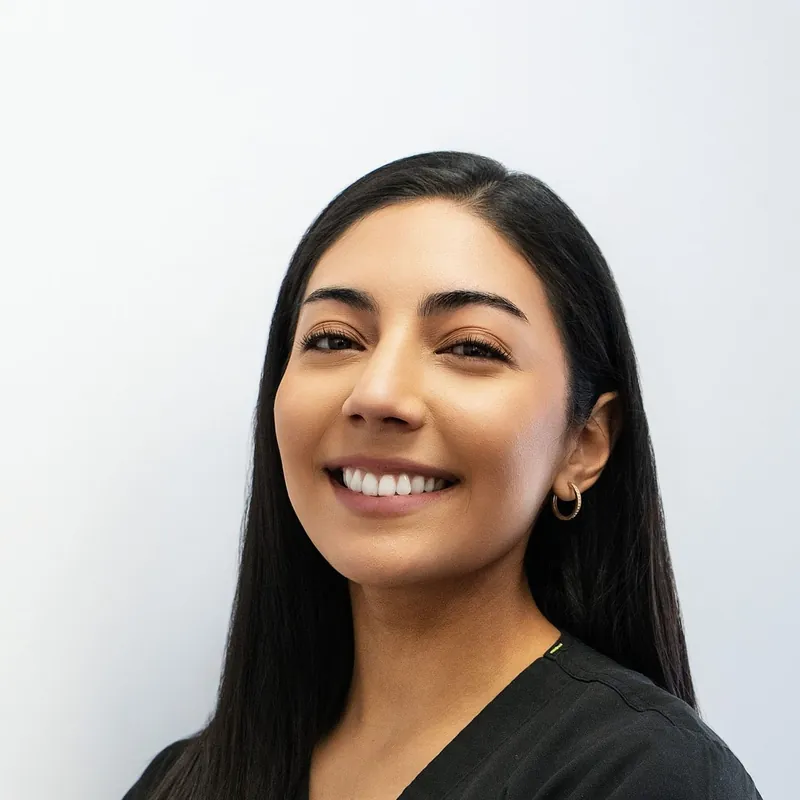 Dani Okoro, a woman with long dark hair in black scrubs, smiling