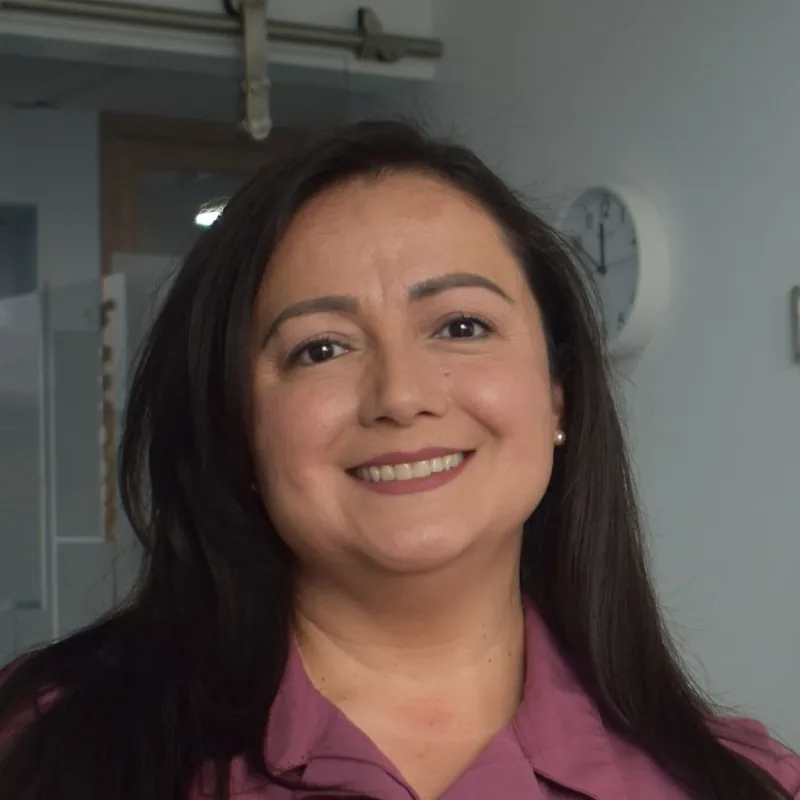 Dr Elena Marsh, a woman in her forties in dark red scrubs, smiling