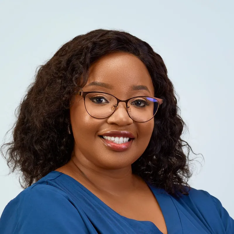 Harriet Cole, a woman in glasses and blue scrubs, smiling