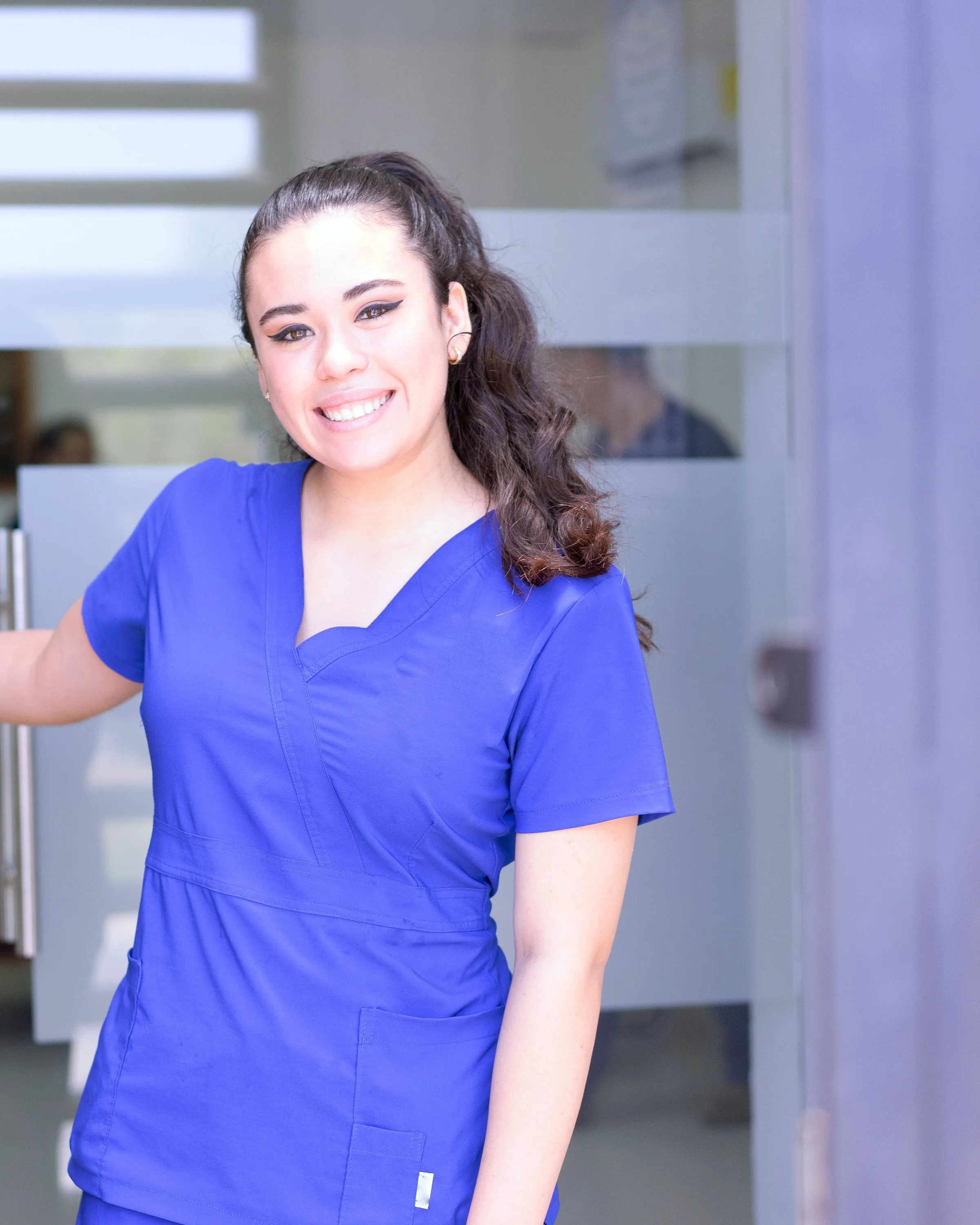 One of our dental nurses, smiling, holding the surgery door open