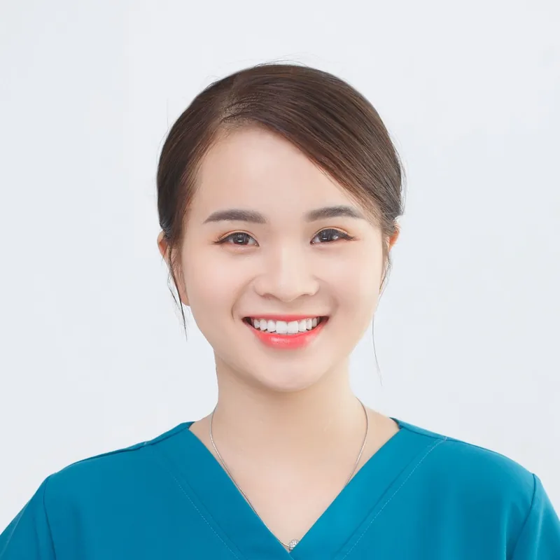 Mei Lin, a young woman in teal scrubs with her hair tied back, smiling